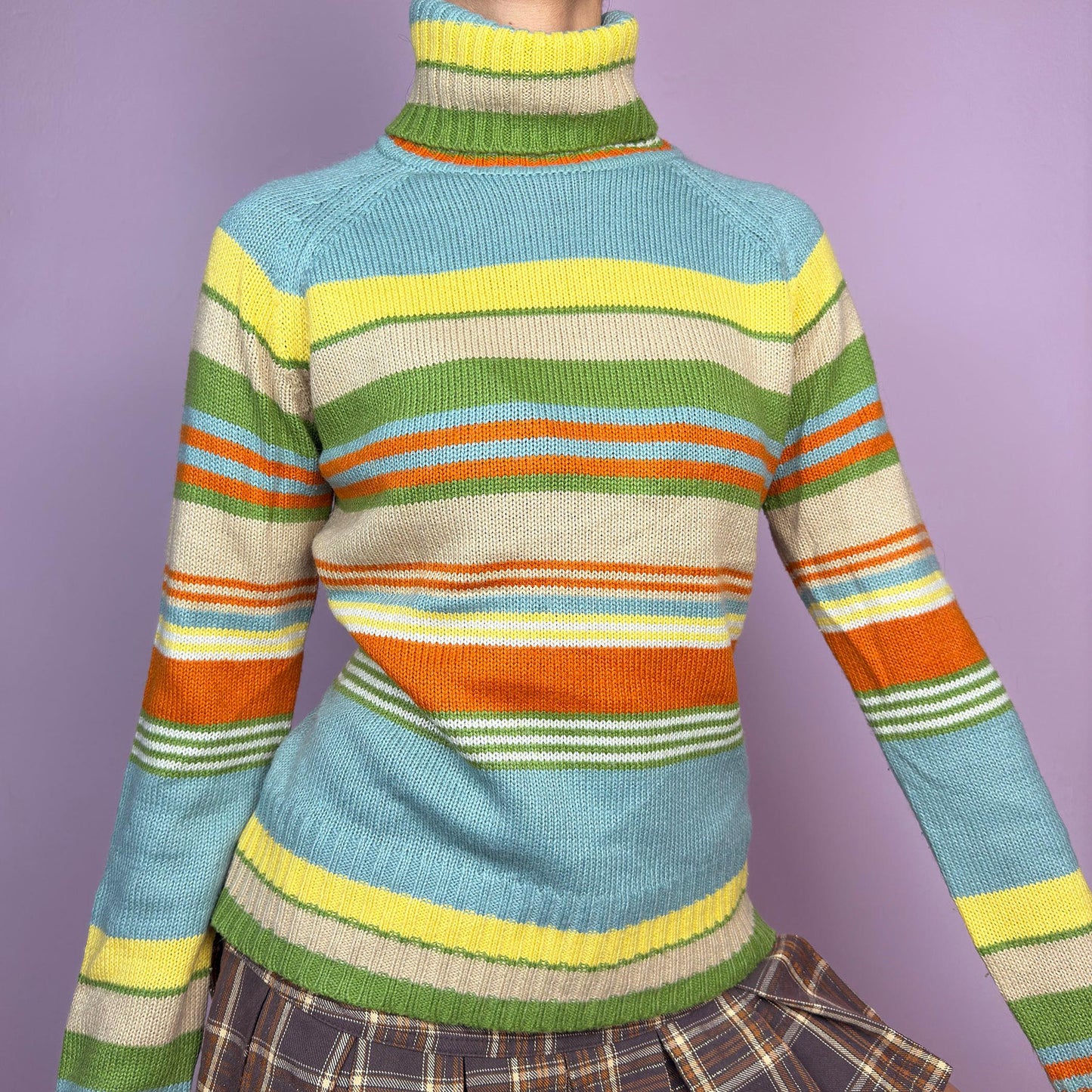 The Y2K Striped Turtleneck Sweater is a vintage 2000s classic featuring a cozy ribbed turtleneck design. Crafted from a knit fabric, it showcases bold multicolor horizontal stripes. adult world shop