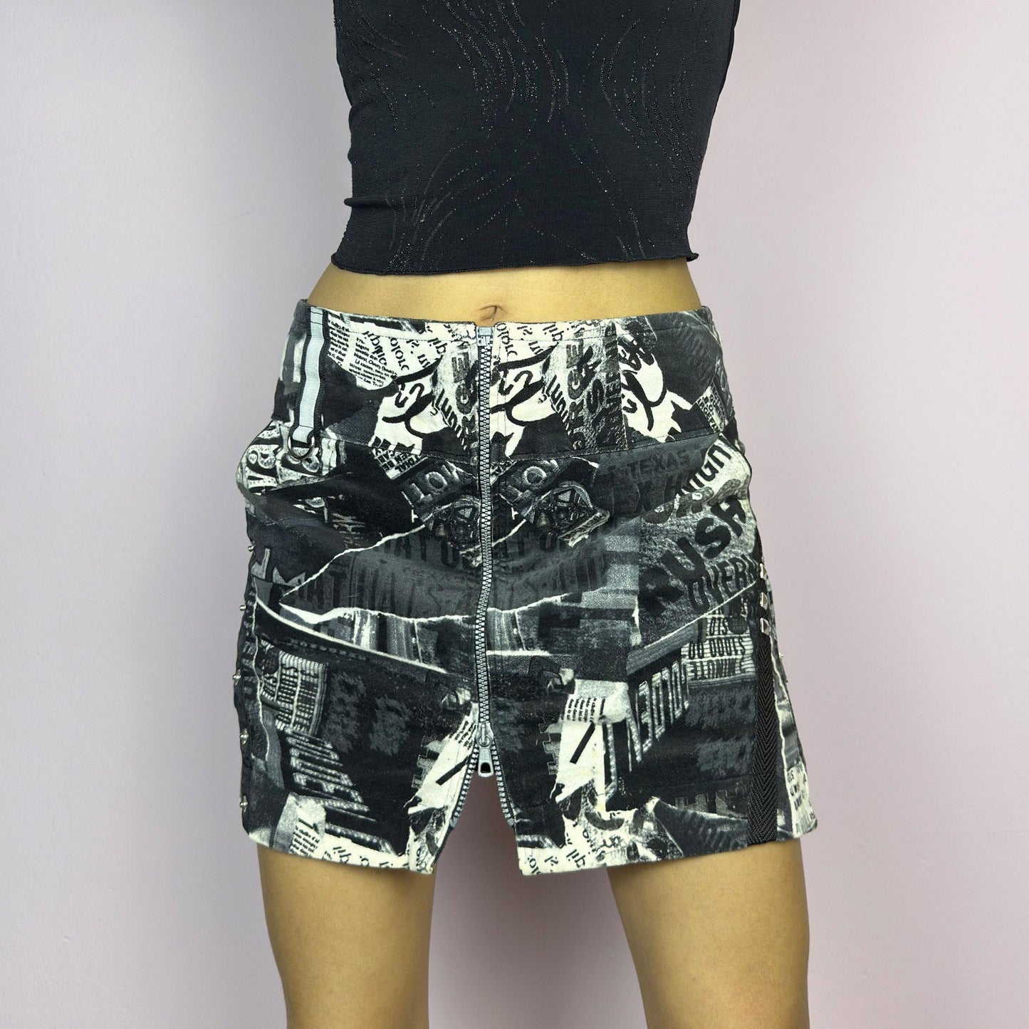 The Y2K Collage Print Mini Skirt is a vintage 2000s piece, featuring an all-over newspaper-inspired collage print in black and white. Designed with a low-rise fit, adjustable front zipper closure and pockets. The added cargo-style details and side zippers enhance its grunge aesthetic, making it perfect for alt, cyber, or casual looks. adult world shop
