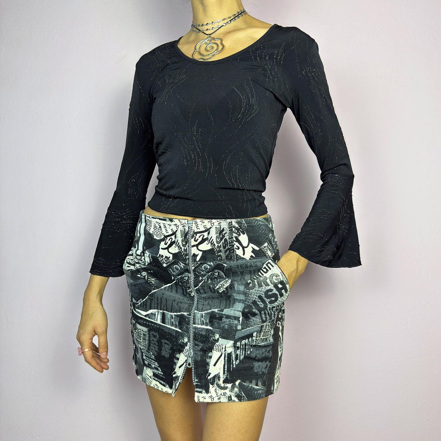 The Y2K Collage Print Mini Skirt is a vintage 2000s piece, featuring an all-over newspaper-inspired collage print in black and white. Designed with a low-rise fit, adjustable front zipper closure and pockets. The added cargo-style details and side zippers enhance its grunge aesthetic, making it perfect for alt, cyber, or casual looks. adult world shop
