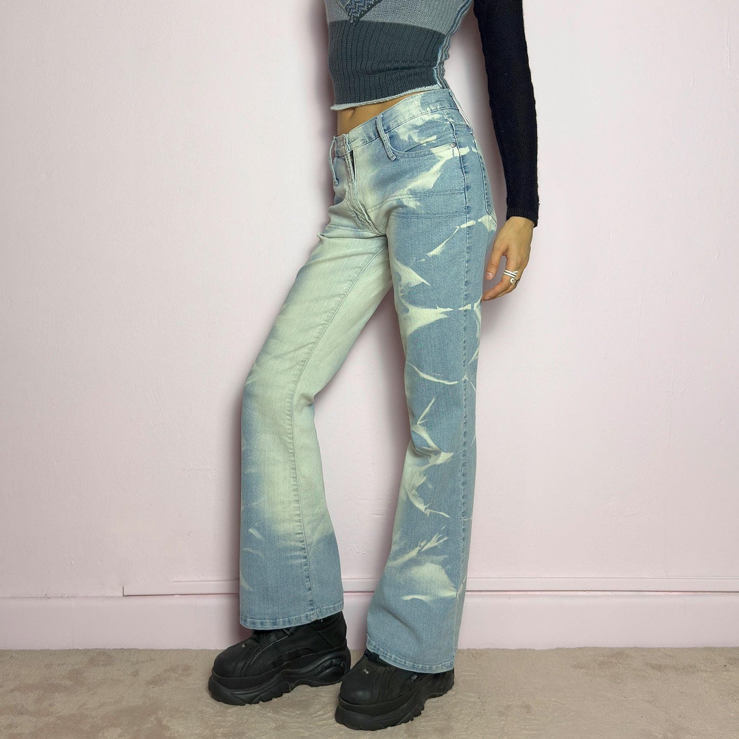 The Y2K Bleached Flare Jeans are a vintage 2000s statement piece featuring a light-wash denim with a bold bleached abstract pattern for a deconstructed, experimental look. Designed with a flattering mid-rise fit, flared legs, button and zipper closure, and pockets, these jeans are a perfect blend of edgy and playful aesthetics. Ideal for standout casual outfits. adult world shop