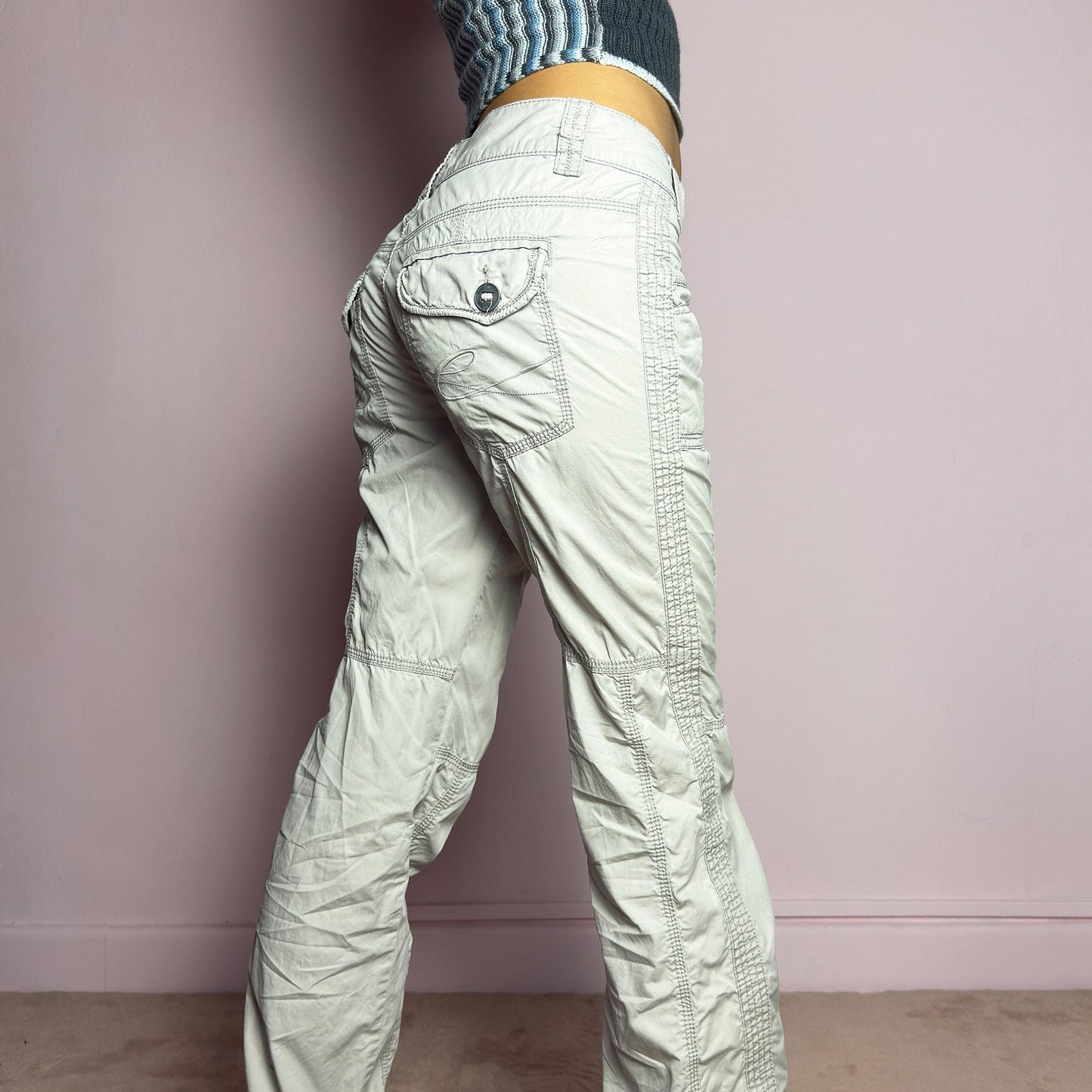The Y2K Gray Low-Rise Pants are a vintage 2000s piece featuring a lightweight, structured fabric with a washed gray tone. Designed with a low-rise waist, button and zipper closure, and pockets, these pants offer a cropped, relaxed straight-leg fit with contrast stitching and panel detailing for a utilitarian-inspired aesthetic. Perfect for streetwear and casual grunge looks. adult world shop
