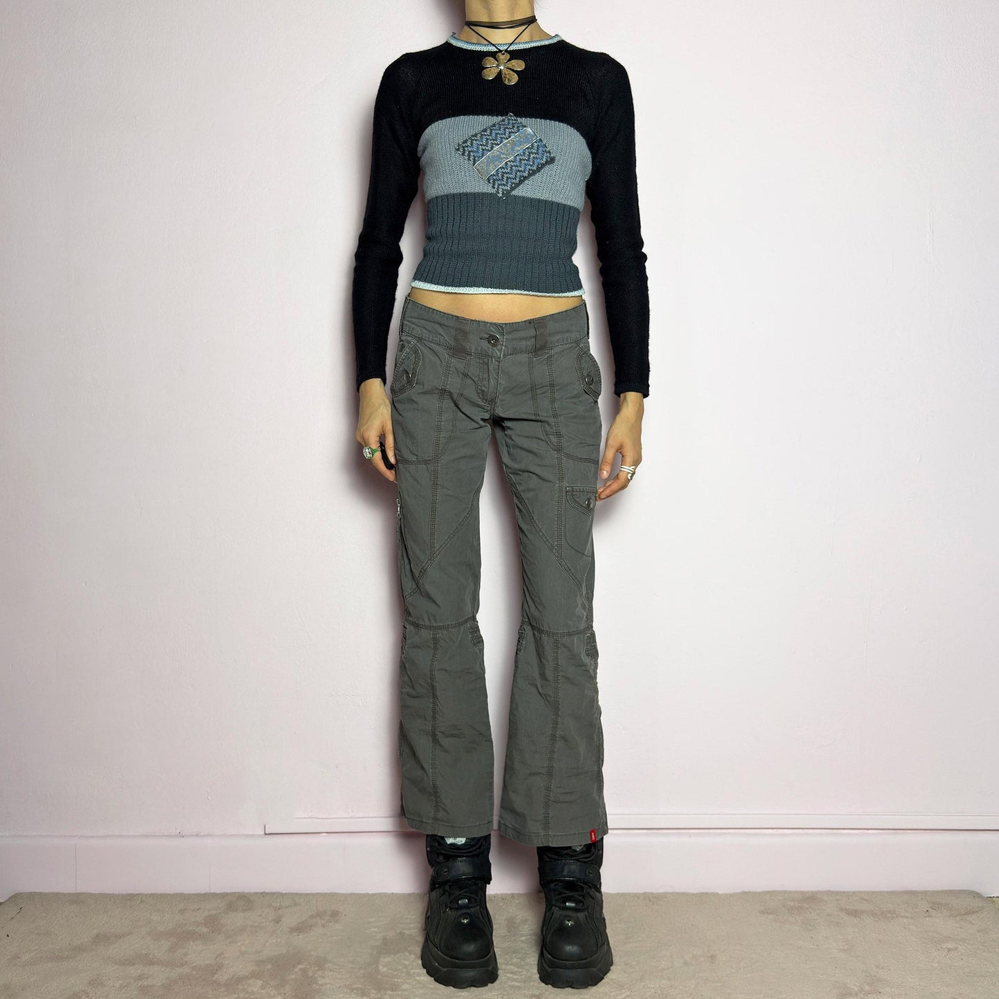 The Y2K Low-Rise Cargo Pants are a vintage 2000s piece featuring a washed gray tone with contrast stitching. Designed with a low-rise fit, button and zipper closure, and multiple cargo-style pockets, these pants have panel detailing and exposed seams that enhance their utilitarian aesthetic. The cropped straight-leg cut adds a modern touch, making them perfect for grunge and streetwear-inspired outfits. adult world shop