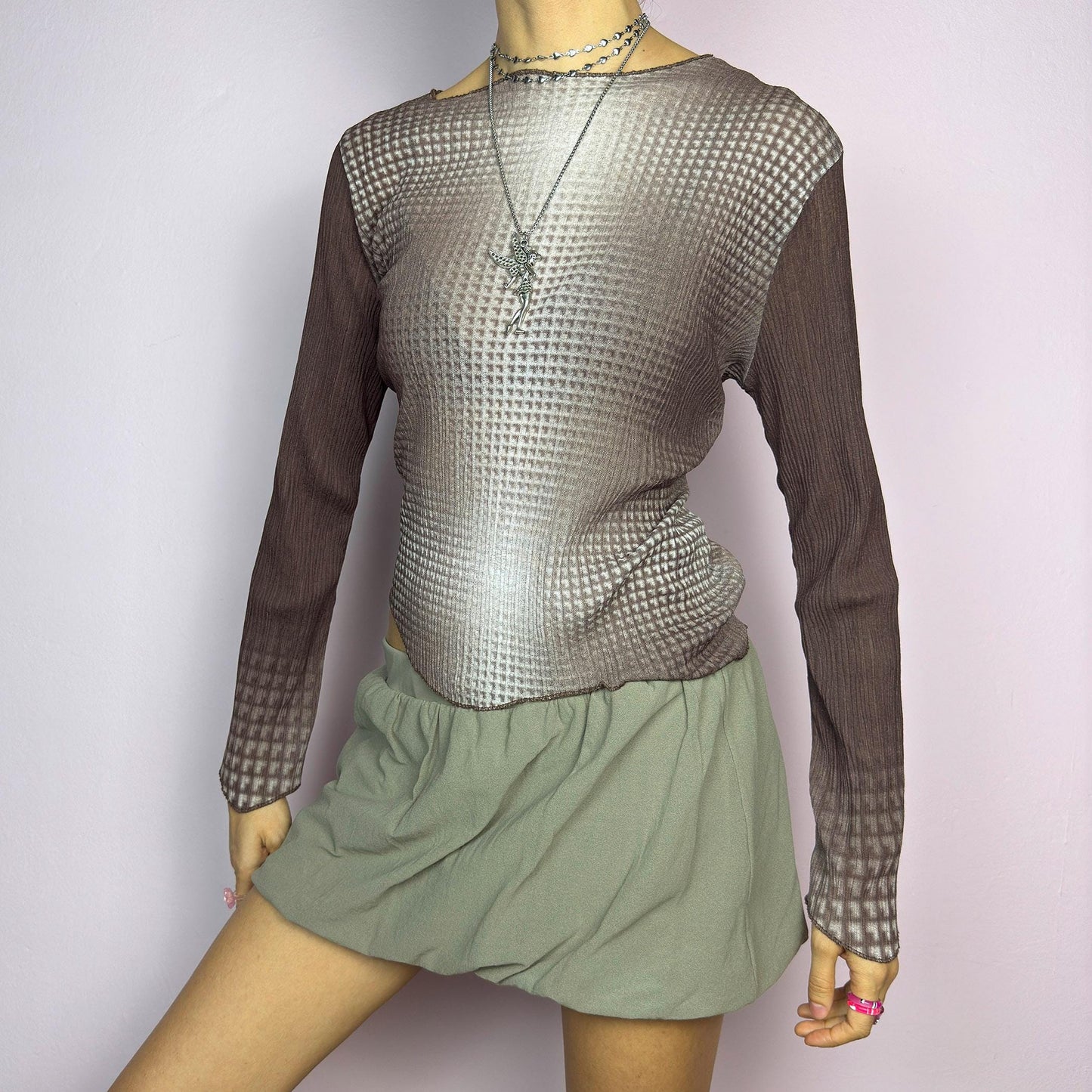 The Y2K Brown Ombre Gradient Top is a vintage 2000s semi-sheer stretchy top featuring a unique ombre gradient print that fades from deep brown to a soft beige. Designed with a subtle asymmetric cut, ribbed texture, and long sleeves, this statement piece adds a futuristic yet earthy touch to casual and streetwear outfits. Perfect for a sleek, edgy look. adult world shop