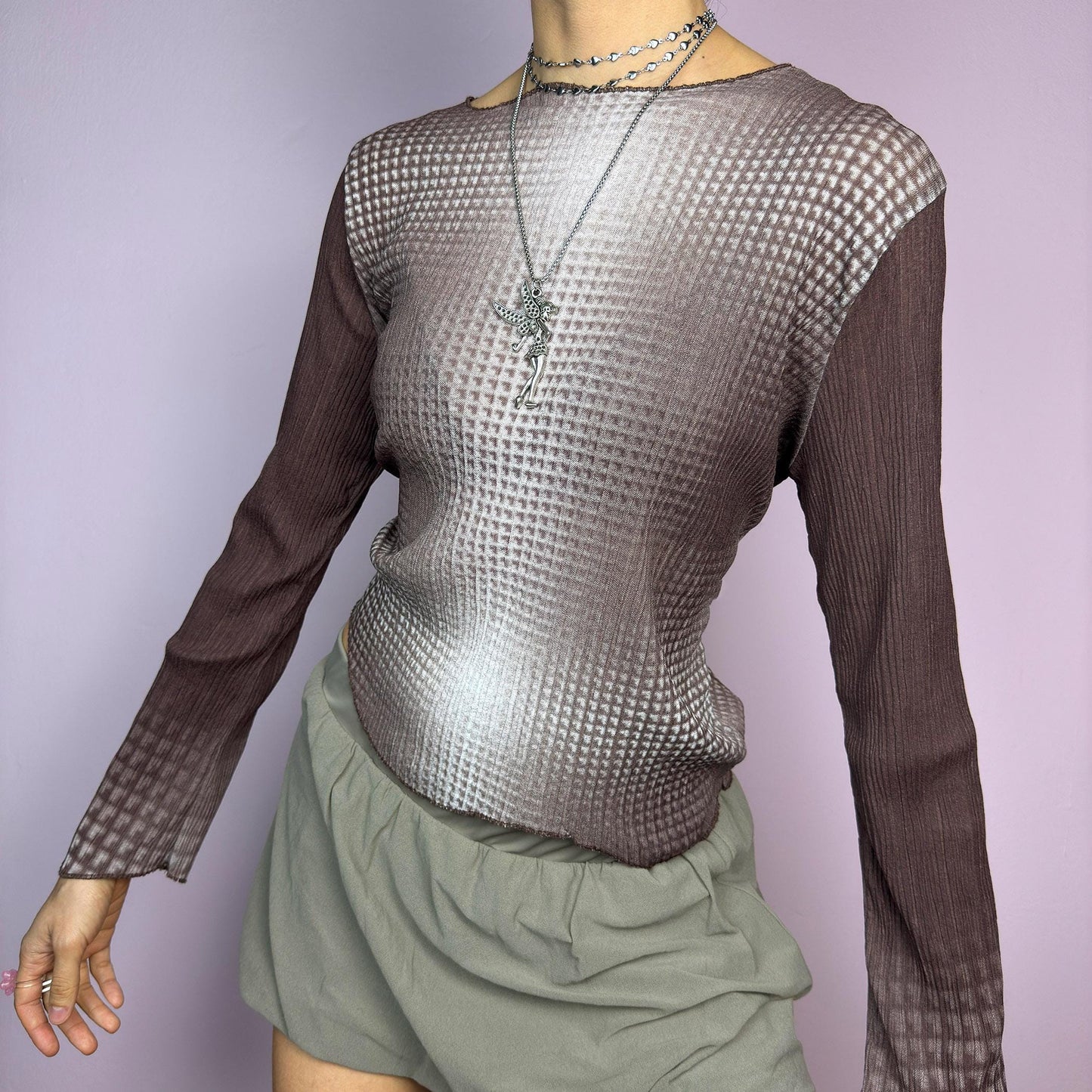 The Y2K Brown Ombre Gradient Top is a vintage 2000s semi-sheer stretchy top featuring a unique ombre gradient print that fades from deep brown to a soft beige. Designed with a subtle asymmetric cut, ribbed texture, and long sleeves, this statement piece adds a futuristic yet earthy touch to casual and streetwear outfits. Perfect for a sleek, edgy look. adult world shop