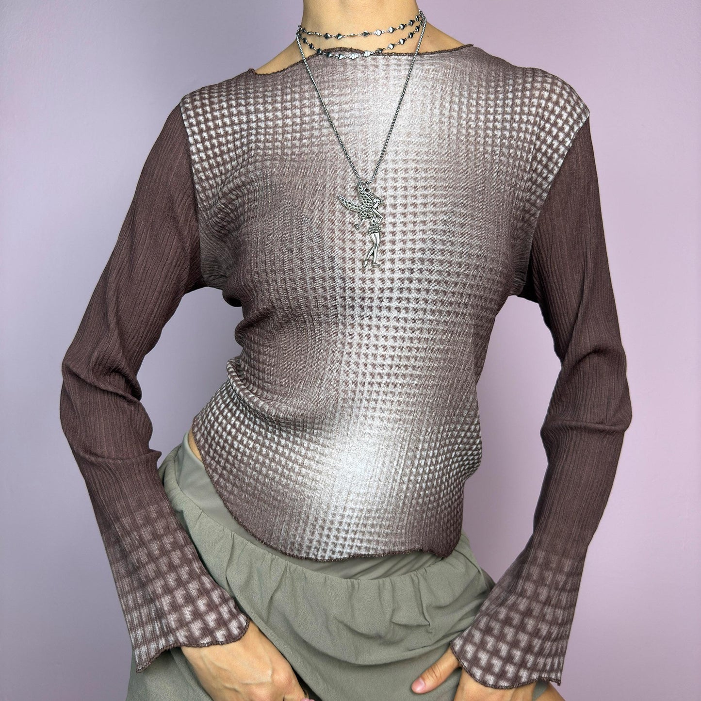 The Y2K Brown Ombre Gradient Top is a vintage 2000s semi-sheer stretchy top featuring a unique ombre gradient print that fades from deep brown to a soft beige. Designed with a subtle asymmetric cut, ribbed texture, and long sleeves, this statement piece adds a futuristic yet earthy touch to casual and streetwear outfits. Perfect for a sleek, edgy look. adult world shop