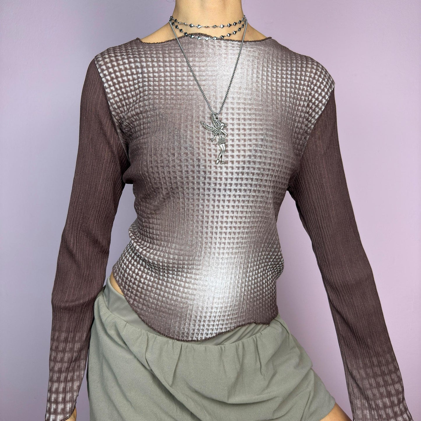 The Y2K Brown Ombre Gradient Top is a vintage 2000s semi-sheer stretchy top featuring a unique ombre gradient print that fades from deep brown to a soft beige. Designed with a subtle asymmetric cut, ribbed texture, and long sleeves, this statement piece adds a futuristic yet earthy touch to casual and streetwear outfits. Perfect for a sleek, edgy look. adult world shop