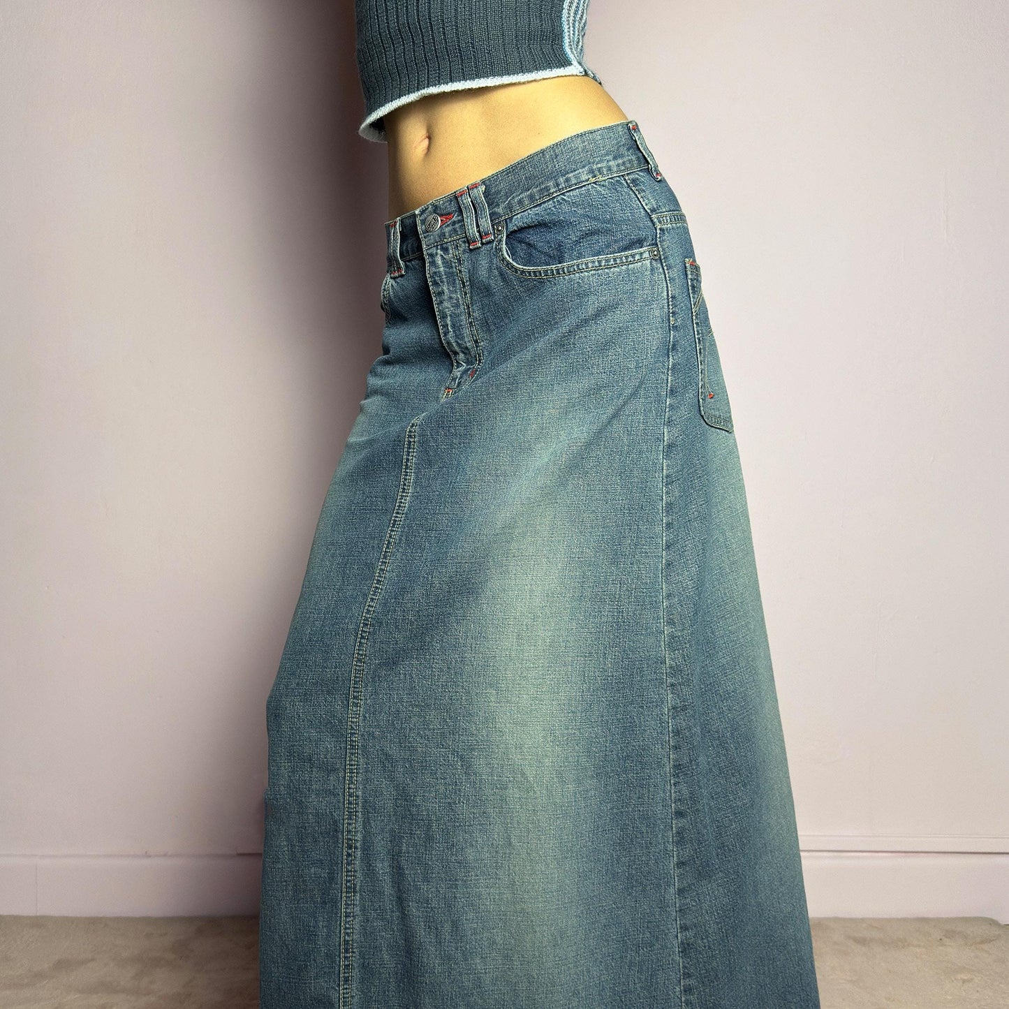 The Y2K Denim Maxi Skirt is a vintage 2000s essential featuring a structured denim fabric in a classic blue wash with subtle fading details. Designed with a mid-rise fit, button and zipper closure, and functional pockets, this skirt offers a sleek yet relaxed silhouette. The back slit adds ease of movement, making it perfect for casual everyday wear. adult world shop