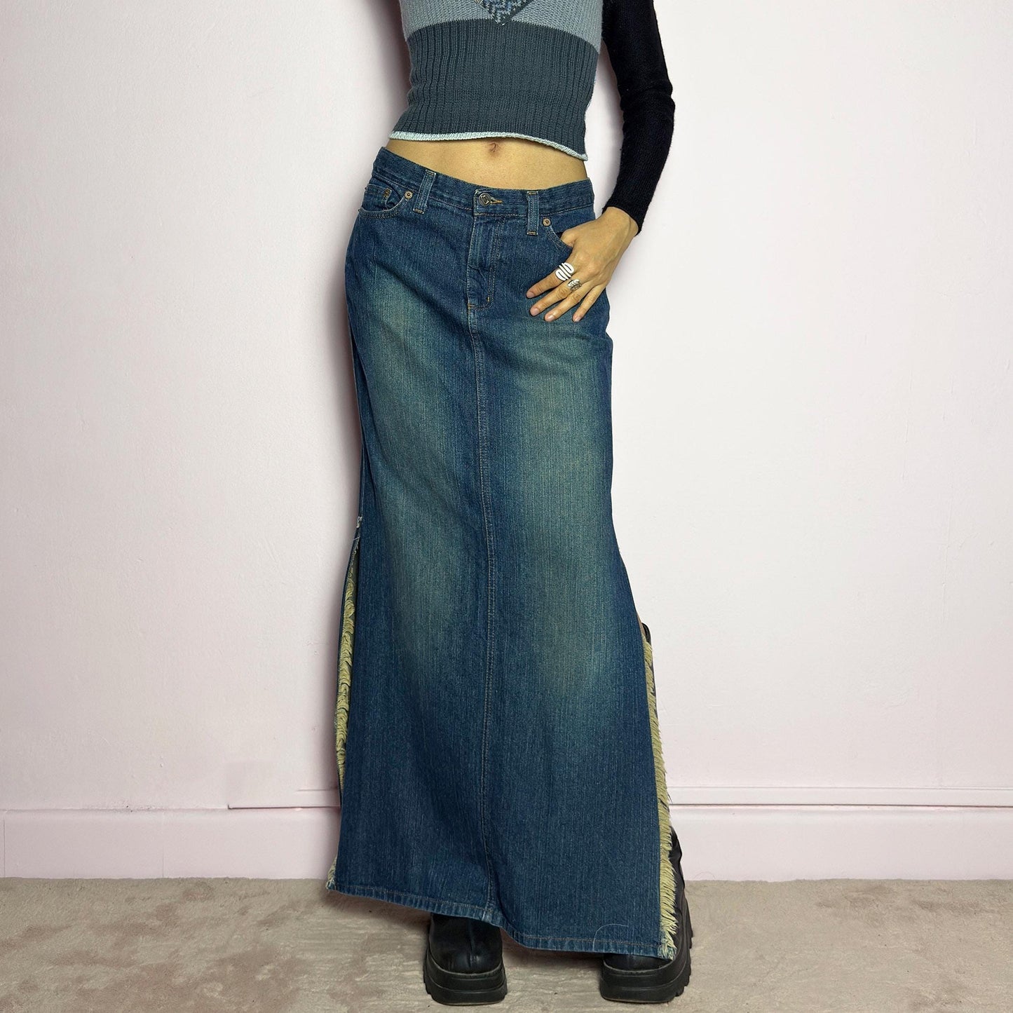 The Y2K Denim Side Slit Maxi Skirt is a vintage 2000s statement piece featuring a structured mid-rise fit and a sleek, elongated silhouette. Designed with frayed side slit details, a button and zipper closure, and classic five-pocket styling, this skirt is perfect for casual streetwear looks. adult world shop