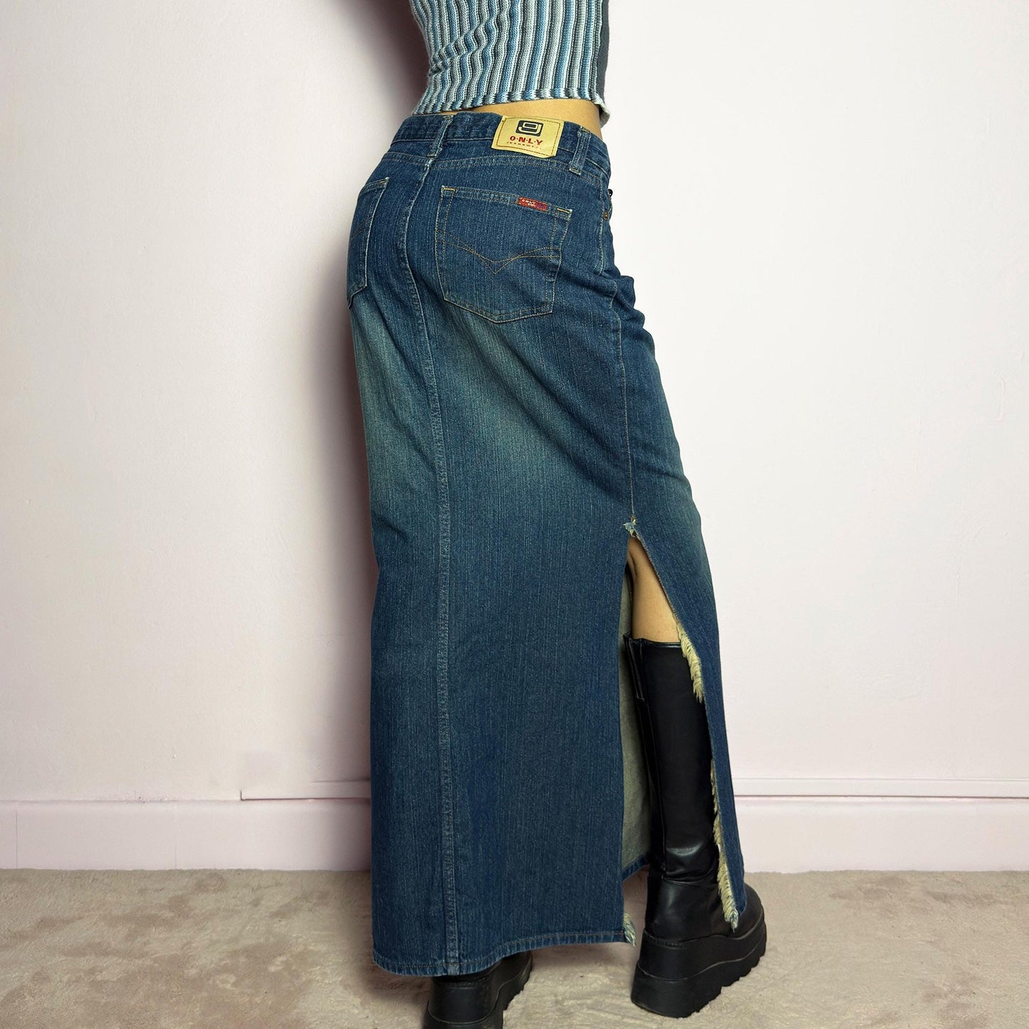 The Y2K Denim Side Slit Maxi Skirt is a vintage 2000s statement piece featuring a structured mid-rise fit and a sleek, elongated silhouette. Designed with frayed side slit details, a button and zipper closure, and classic five-pocket styling, this skirt is perfect for casual streetwear looks. adult world shop