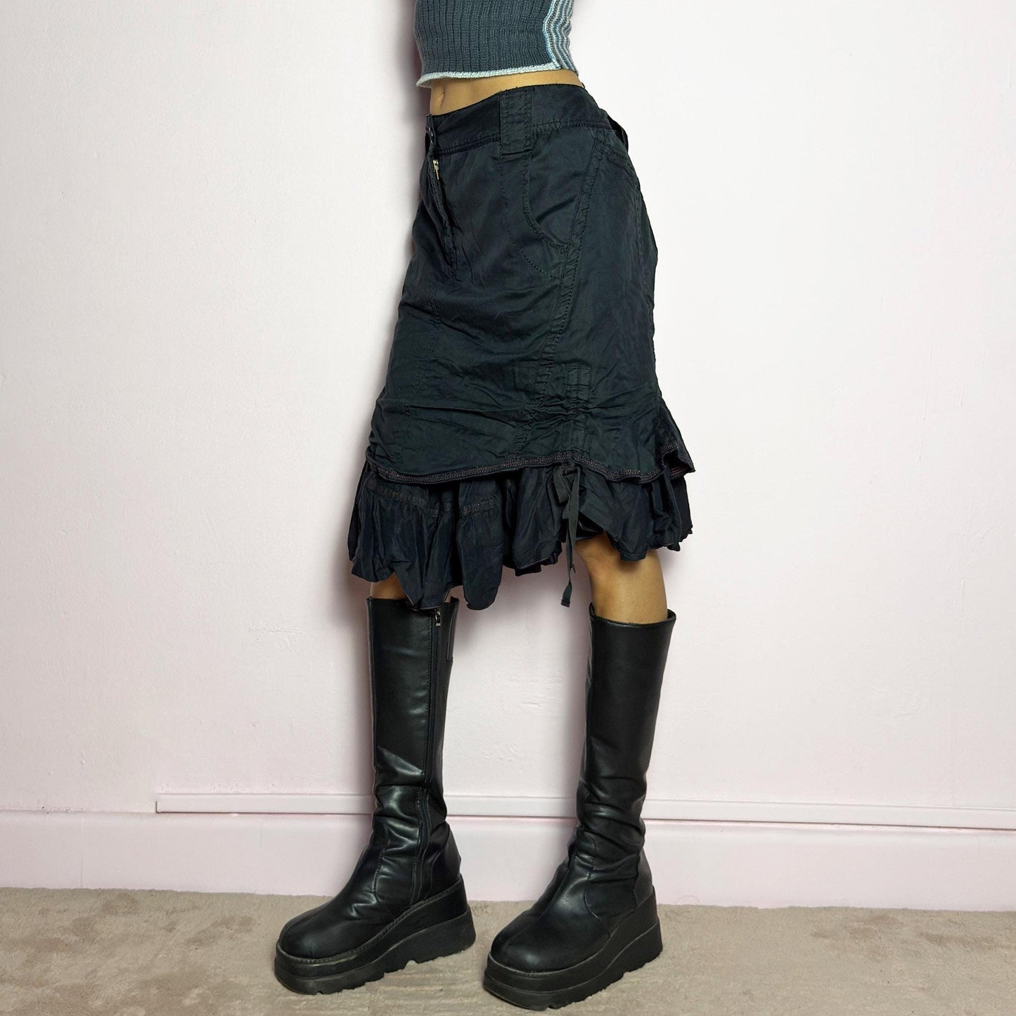The Y2K Black Layered Skirt by Marithé François Girbaud is a vintage 2000s statement piece featuring a structured design with ruched details and ruffled layers for added texture and movement. Designed with a mid-rise fit, button and zipper closure, embroidered side detail, and an asymmetrical hem, this skirt blends edgy streetwear vibes with a playful, gothic aesthetic. Perfect for casual grunge and alternative looks. adult world shop