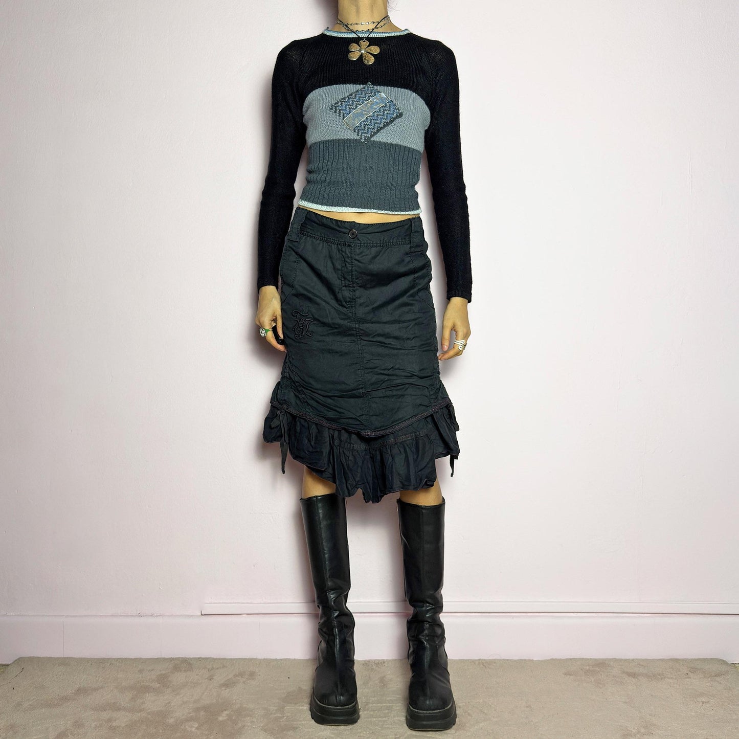 The Y2K Black Layered Skirt by Marithé François Girbaud is a vintage 2000s statement piece featuring a structured design with ruched details and ruffled layers for added texture and movement. Designed with a mid-rise fit, button and zipper closure, embroidered side detail, and an asymmetrical hem, this skirt blends edgy streetwear vibes with a playful, gothic aesthetic. Perfect for casual grunge and alternative looks. adult world shop