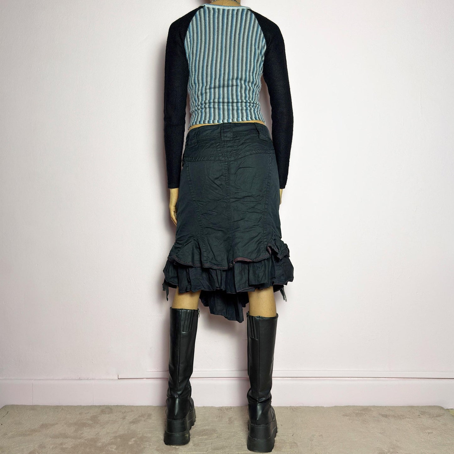 The Y2K Black Layered Skirt by Marithé François Girbaud is a vintage 2000s statement piece featuring a structured design with ruched details and ruffled layers for added texture and movement. Designed with a mid-rise fit, button and zipper closure, embroidered side detail, and an asymmetrical hem, this skirt blends edgy streetwear vibes with a playful, gothic aesthetic. Perfect for casual grunge and alternative looks. adult world shop