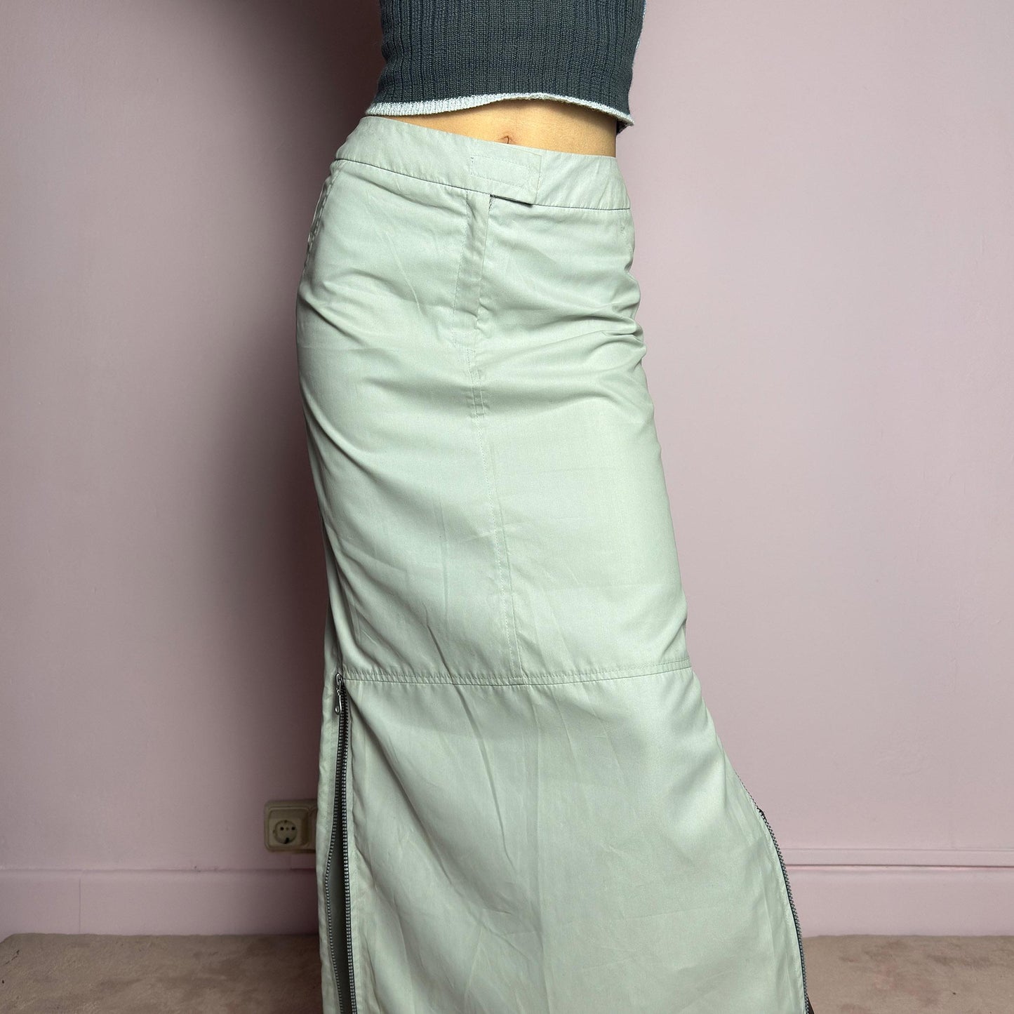 The Y2K Light Gray Maxi Skirt is a vintage 2000s piece with a sleek, futuristic aesthetic. Featuring a structured fit, and a high-rise waist, this skirt is designed for a modern, minimal look. Made from lightweight fabric, it offers a flattering silhouette with dual side zipper slits for adjustable styling. Perfect for casual, streetwear, or cyber-inspired avant-garde outfits. adult world shop