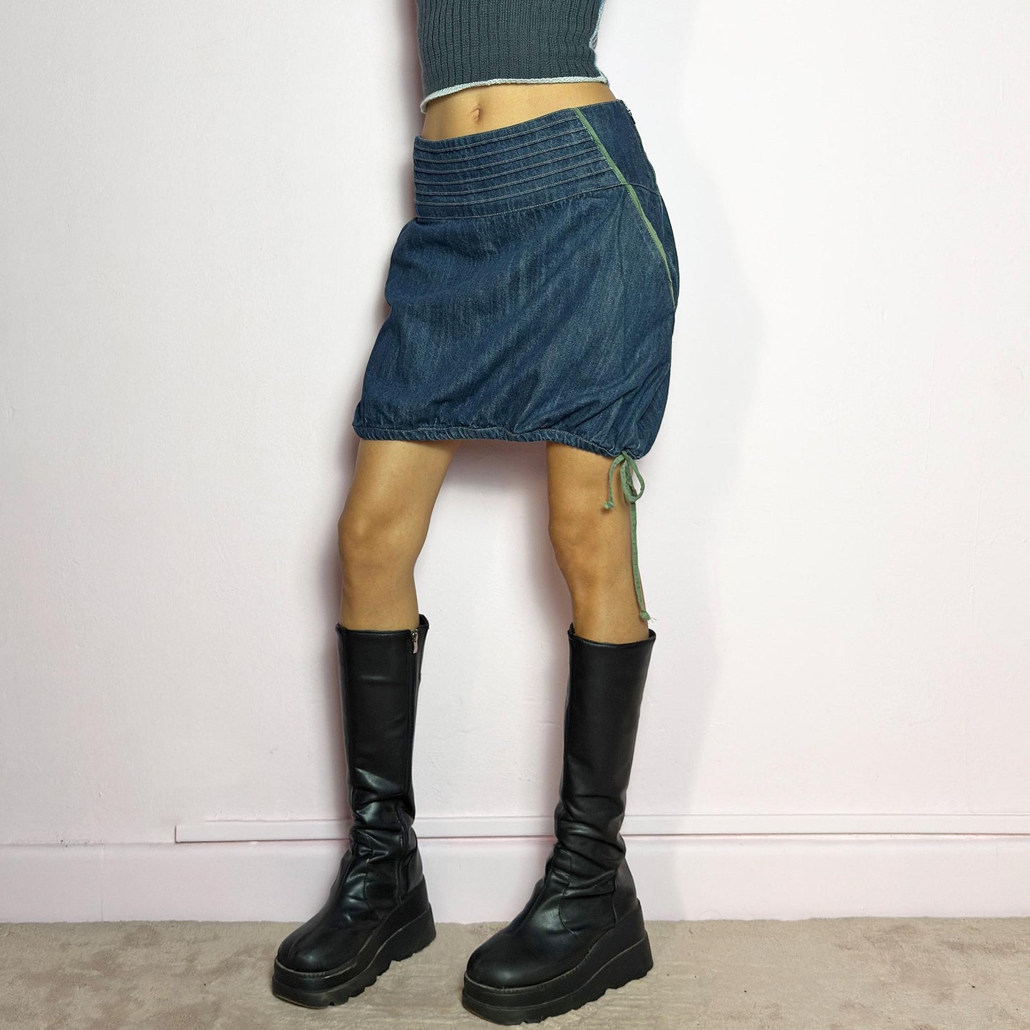 The Y2K Denim Bubble Mini Skirt is a vintage 2000s piece featuring a dark wash denim with unique structured pleating at the waist. Designed with an adjustable bubble hem with drawstrings for a customizable fit, this skirt blends playful and edgy aesthetics. It also includes a side zipper closure. Perfect for statement streetwear looks. adult world shop