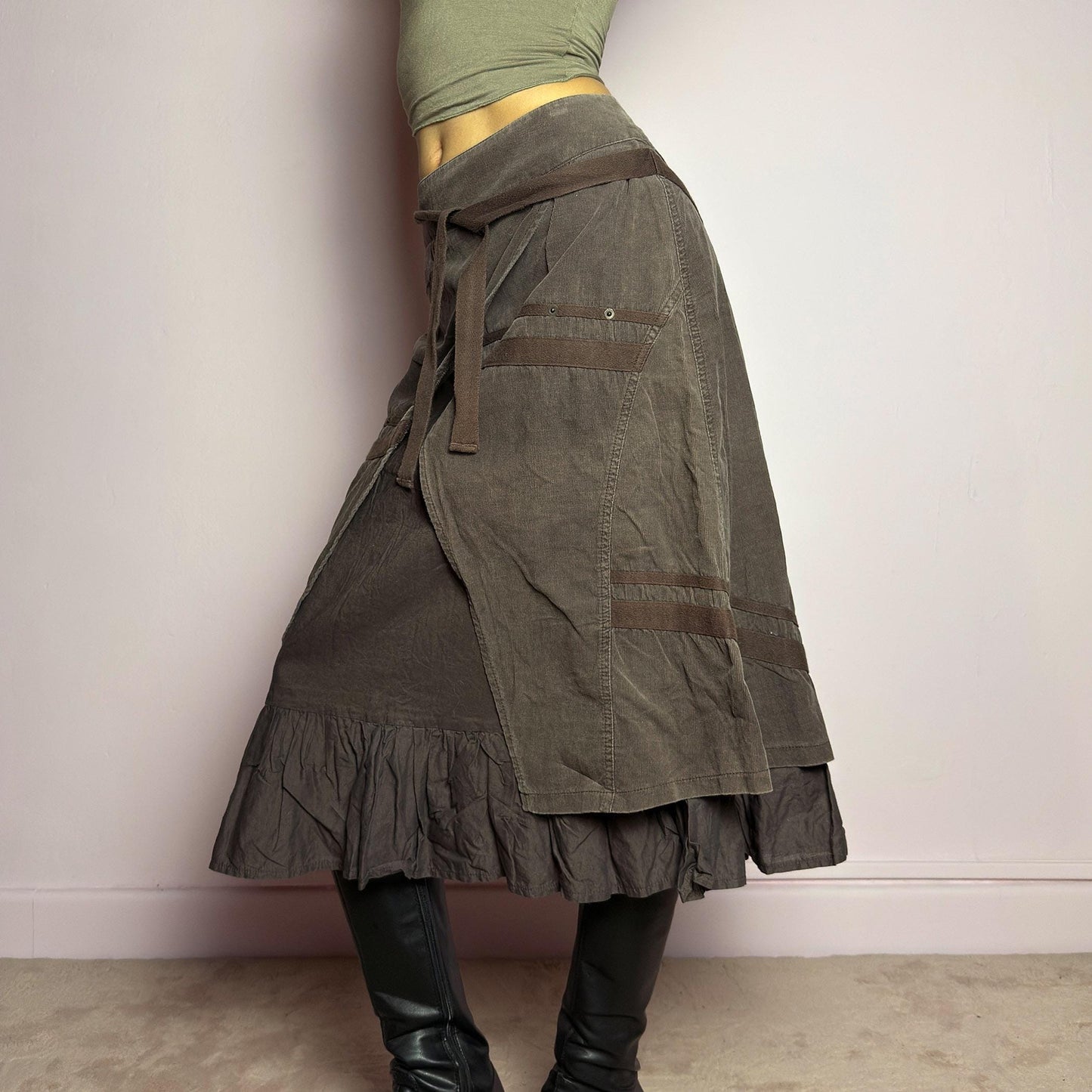 The Y2K Layered Brown Midi Skirt is a unique vintage 2000s piece featuring an asymmetric wrap design with a layered ruffle hem. Made from corduroy-cotton fabric, it includes tie closures for an adjustable fit, a back zipper closure, and subtle stitched detailing that adds a deconstructed touch. Perfect for earthy, bohemian, or avant-garde styling. adult world shop