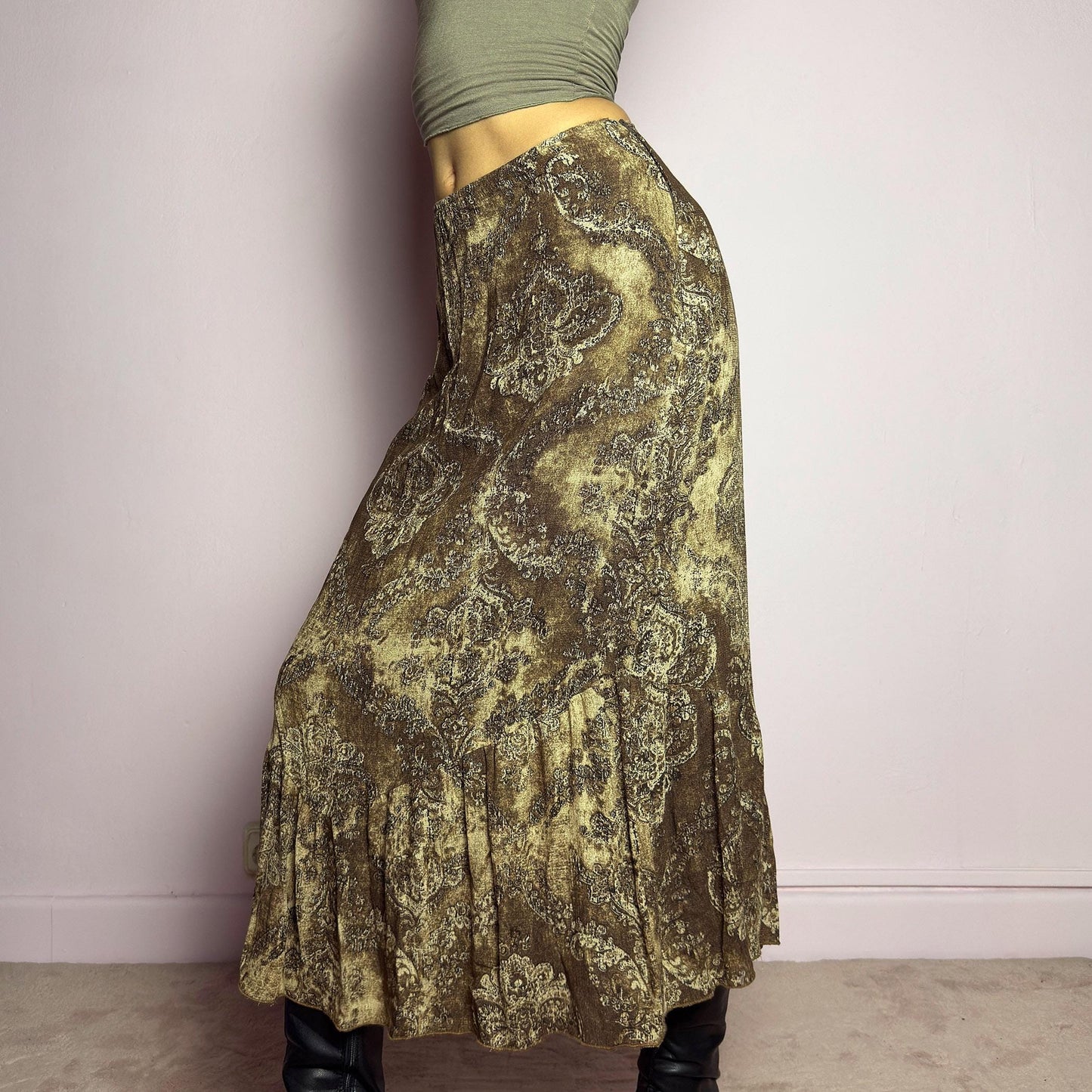 The Y2K Brown Paisley Midi Skirt is a vintage 2000s piece featuring a baroque-inspired paisley print. Designed with an earthy, whimsical aesthetic, this skirt has a flowy silhouette with subtle ruffle tiered details at the hem. It features a side zipper closure with an elastic waist. Perfect for grunge and bohemian-inspired outfits. adult world shop