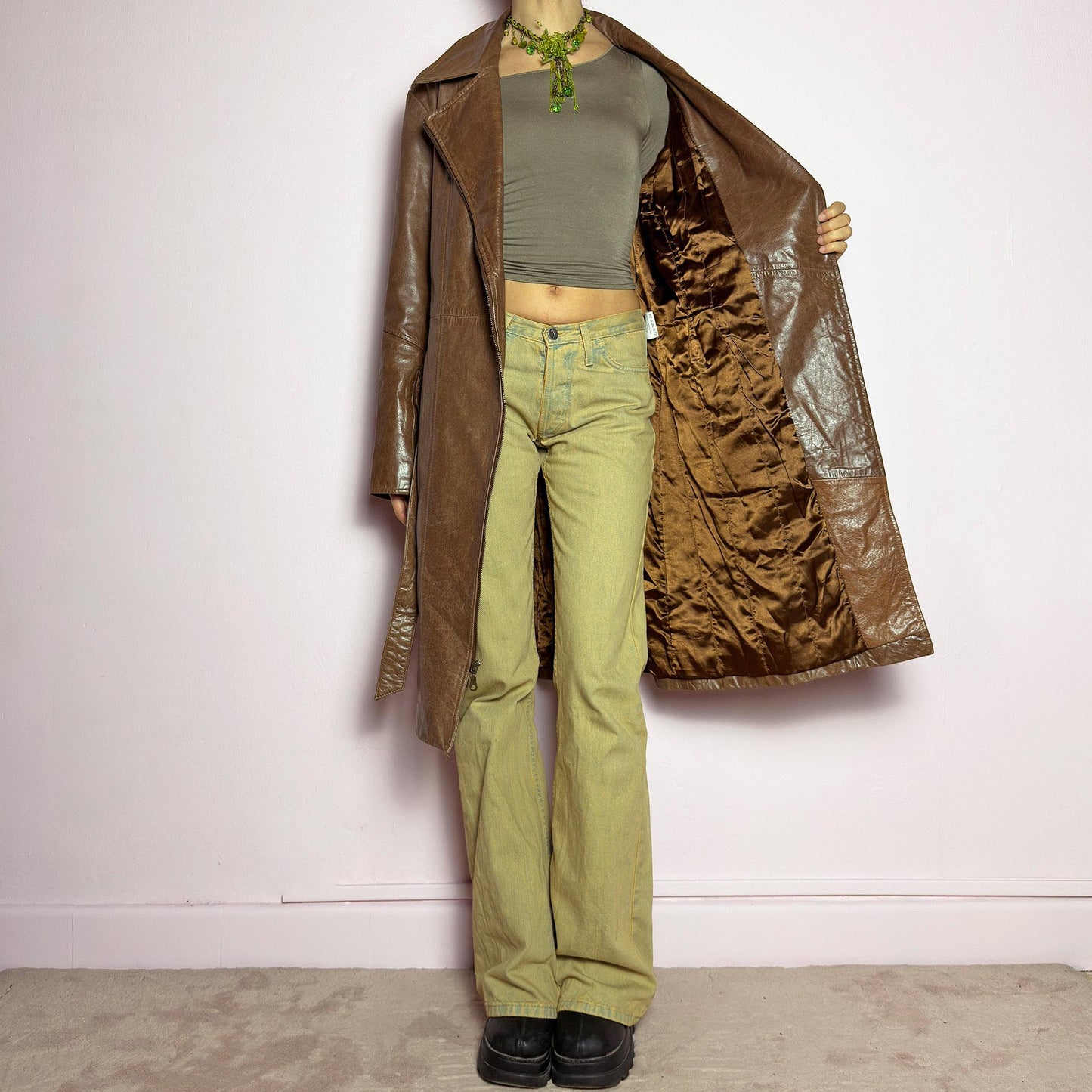 The Y2K Long Brown Leather Coat is a heavy, structured vintage 2000s piece crafted from genuine leather. It features an asymmetrical zip closure, a wide lapel collar, and a belted waist for a cinched silhouette. The coat includes pockets and a smooth lining for comfort. With its durable construction and timeless design, this vintage long leather coat is perfect for edgy streetwear or sophisticated layering. adult world shop