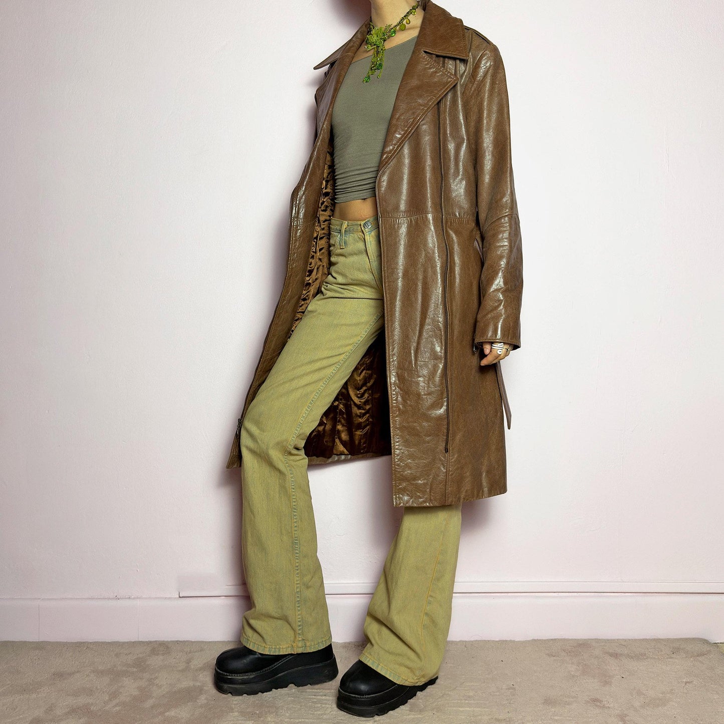 The Y2K Long Brown Leather Coat is a heavy, structured vintage 2000s piece crafted from genuine leather. It features an asymmetrical zip closure, a wide lapel collar, and a belted waist for a cinched silhouette. The coat includes pockets and a smooth lining for comfort. With its durable construction and timeless design, this vintage long leather coat is perfect for edgy streetwear or sophisticated layering. adult world shop