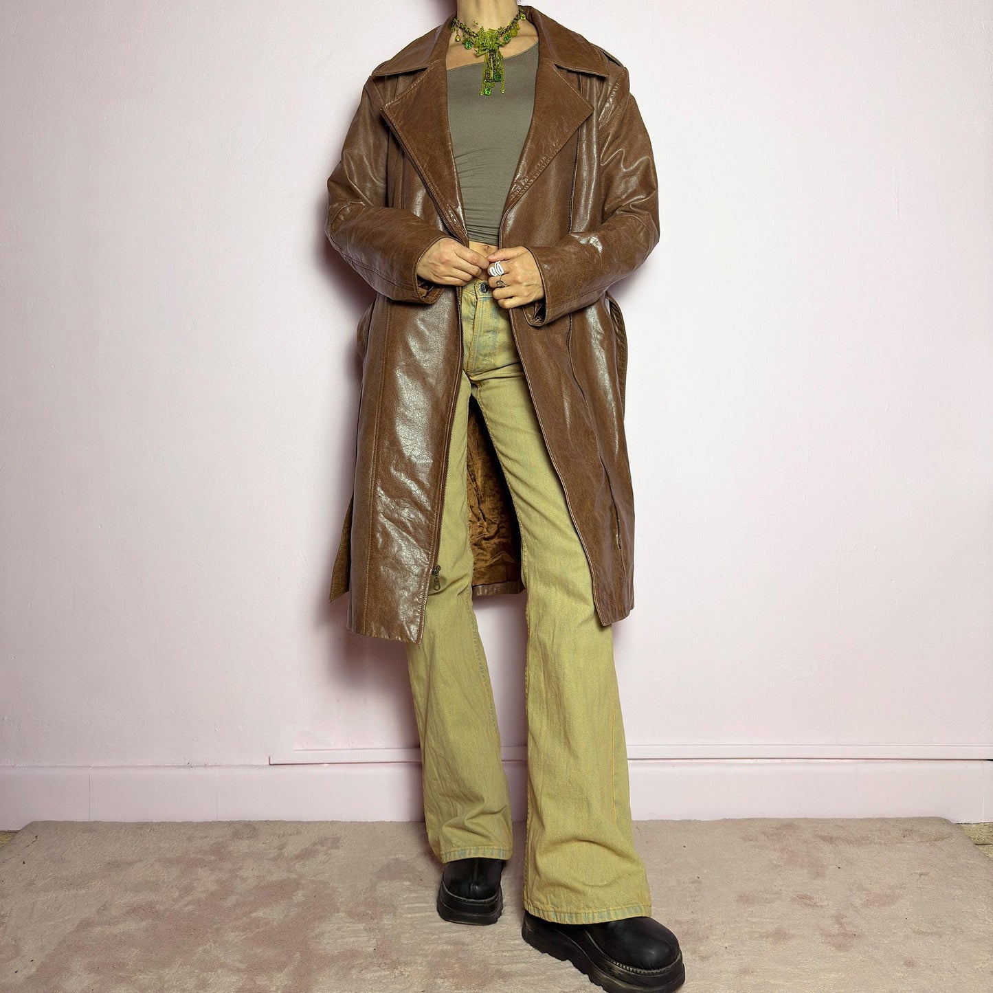 The Y2K Long Brown Leather Coat is a heavy, structured vintage 2000s piece crafted from genuine leather. It features an asymmetrical zip closure, a wide lapel collar, and a belted waist for a cinched silhouette. The coat includes pockets and a smooth lining for comfort. With its durable construction and timeless design, this vintage long leather coat is perfect for edgy streetwear or sophisticated layering. adult world shop
