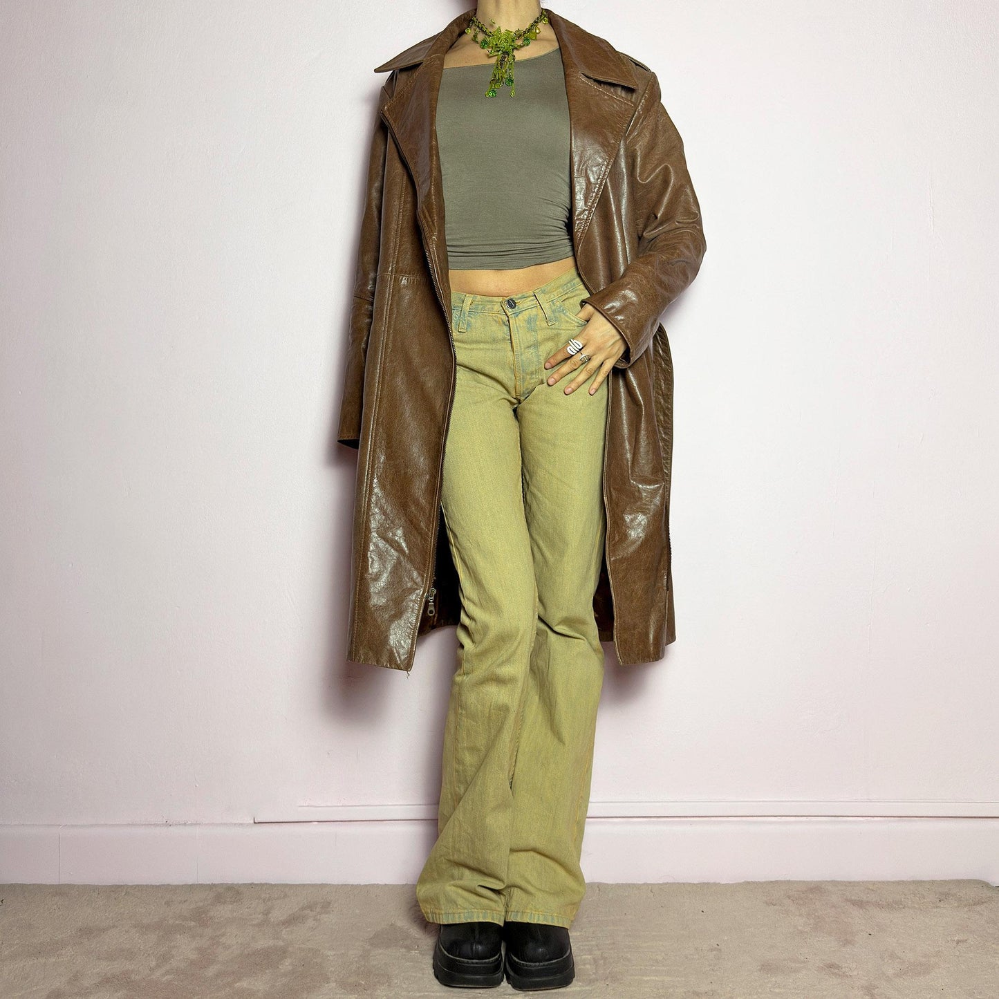 The Y2K Long Brown Leather Coat is a heavy, structured vintage 2000s piece crafted from genuine leather. It features an asymmetrical zip closure, a wide lapel collar, and a belted waist for a cinched silhouette. The coat includes pockets and a smooth lining for comfort. With its durable construction and timeless design, this vintage long leather coat is perfect for edgy streetwear or sophisticated layering. adult world shop
