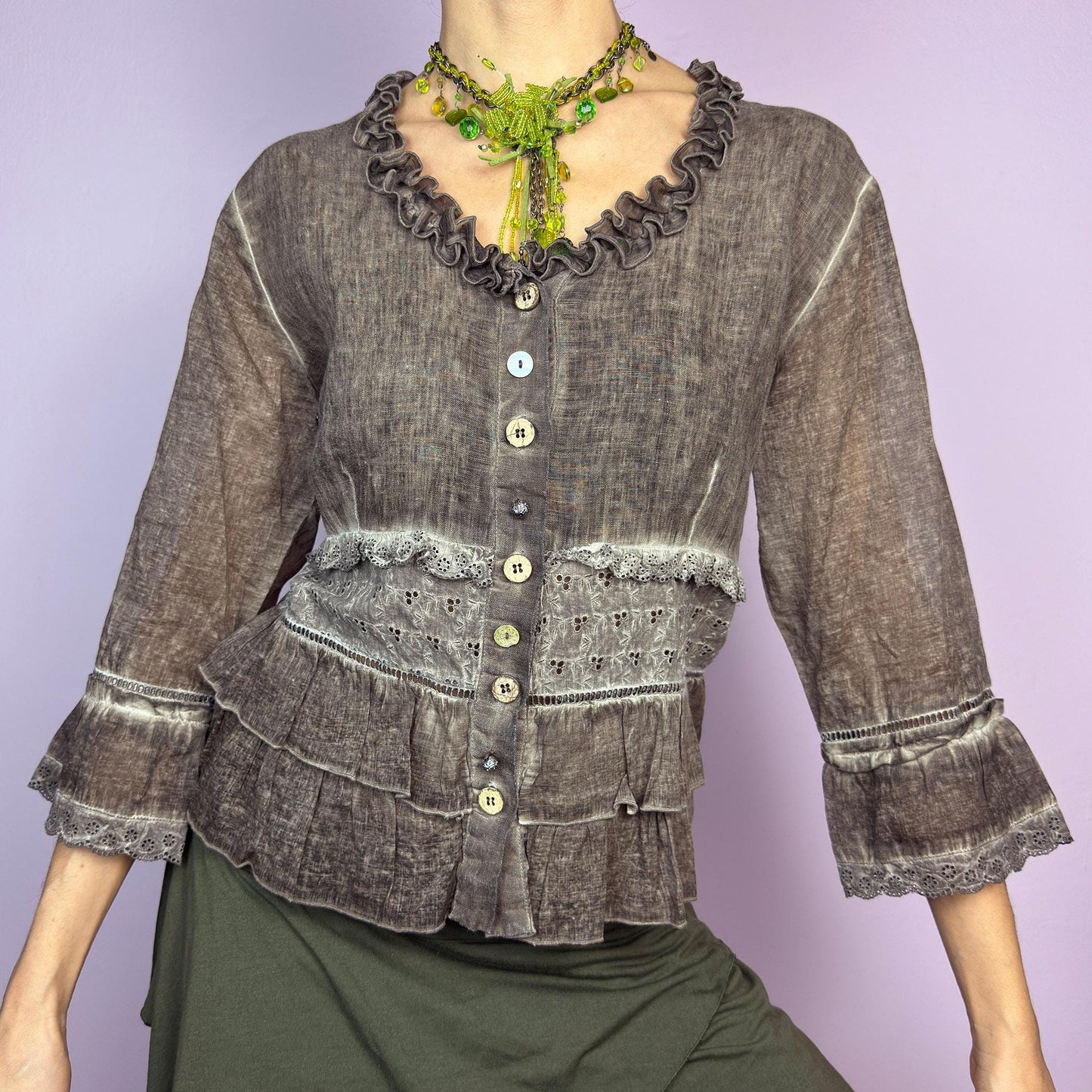 The Y2K Brown Ruffle Frill Blouse is a vintage 2000s piece featuring a faded brown wash with delicate lace trims and tiered ruffle details for a romantic, fairy-grunge aesthetic. Designed with a button-up front, 3/4 bell sleeves, this blouse blends cottagecore and bohemian elements effortlessly. The soft, lightweight fabric makes it perfect for dreamy summer outfits. adult world shop