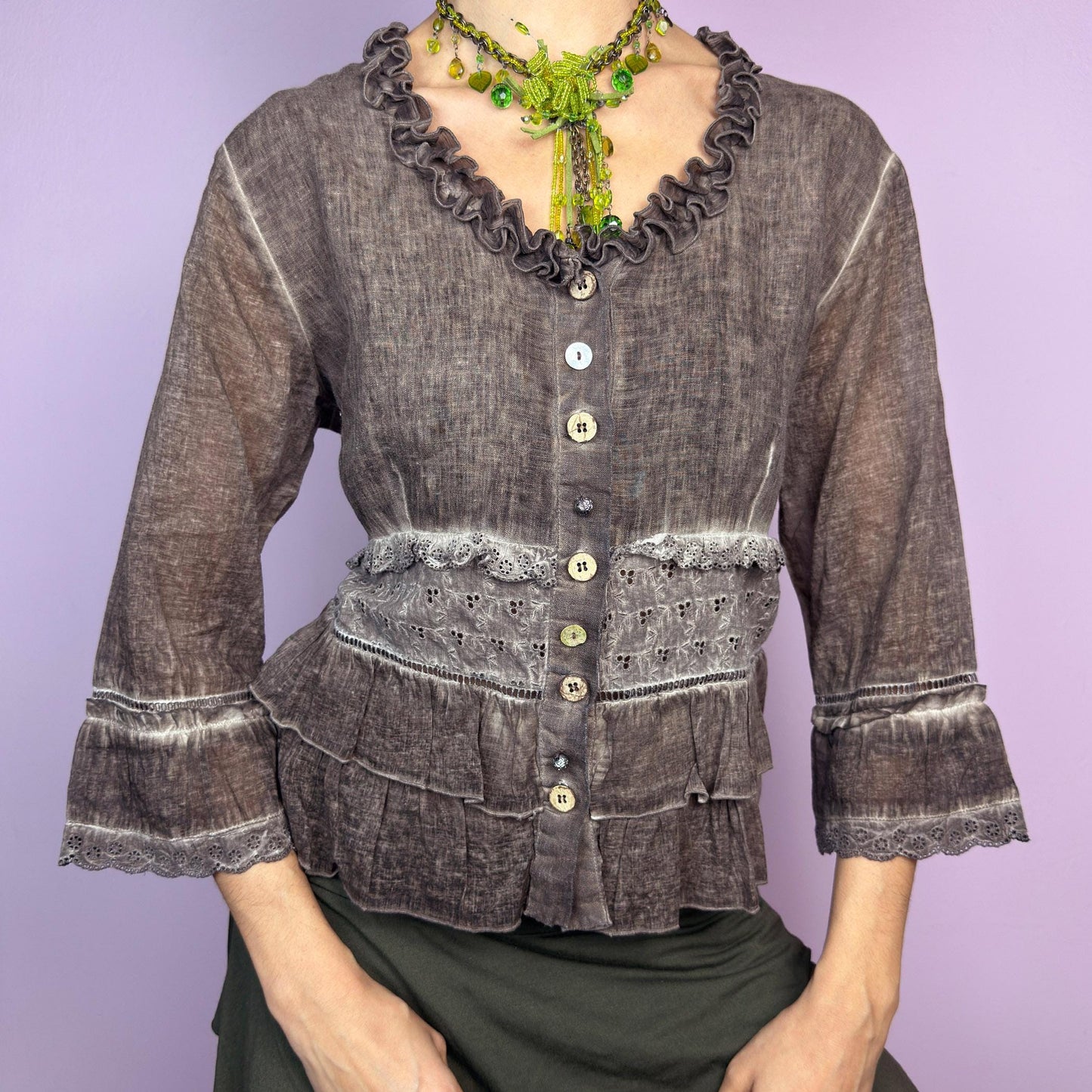The Y2K Brown Ruffle Frill Blouse is a vintage 2000s piece featuring a faded brown wash with delicate lace trims and tiered ruffle details for a romantic, fairy-grunge aesthetic. Designed with a button-up front, 3/4 bell sleeves, this blouse blends cottagecore and bohemian elements effortlessly. The soft, lightweight fabric makes it perfect for dreamy summer outfits. adult world shop