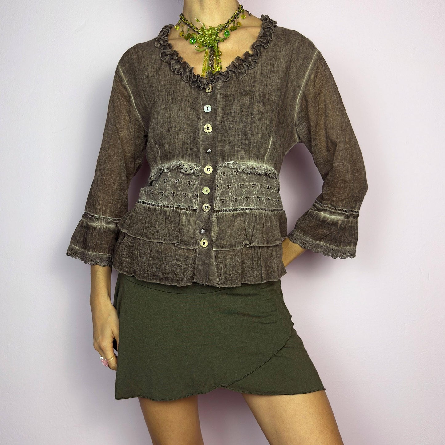 The Y2K Brown Ruffle Frill Blouse is a vintage 2000s piece featuring a faded brown wash with delicate lace trims and tiered ruffle details for a romantic, fairy-grunge aesthetic. Designed with a button-up front, 3/4 bell sleeves, this blouse blends cottagecore and bohemian elements effortlessly. The soft, lightweight fabric makes it perfect for dreamy summer outfits. adult world shop