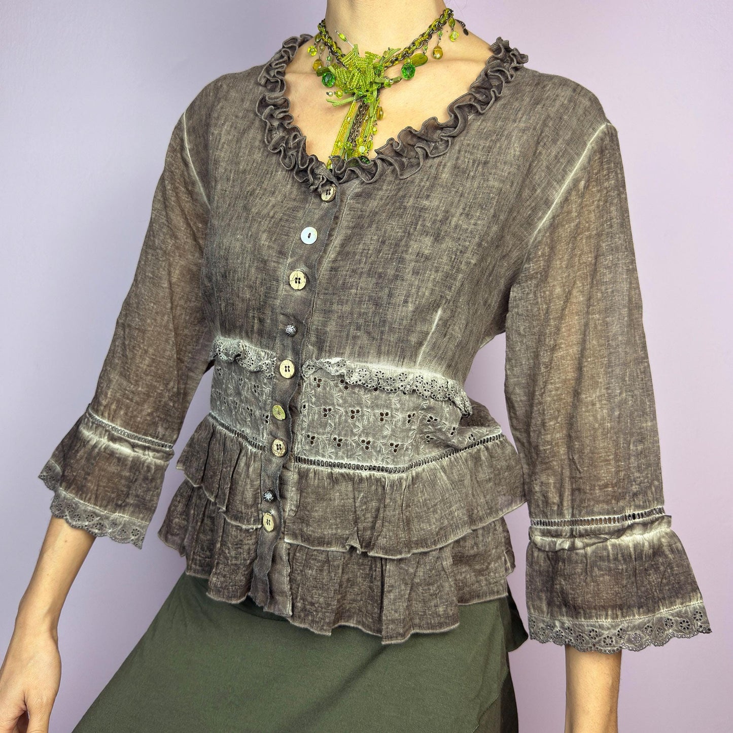 The Y2K Brown Ruffle Frill Blouse is a vintage 2000s piece featuring a faded brown wash with delicate lace trims and tiered ruffle details for a romantic, fairy-grunge aesthetic. Designed with a button-up front, 3/4 bell sleeves, this blouse blends cottagecore and bohemian elements effortlessly. The soft, lightweight fabric makes it perfect for dreamy summer outfits. adult world shop