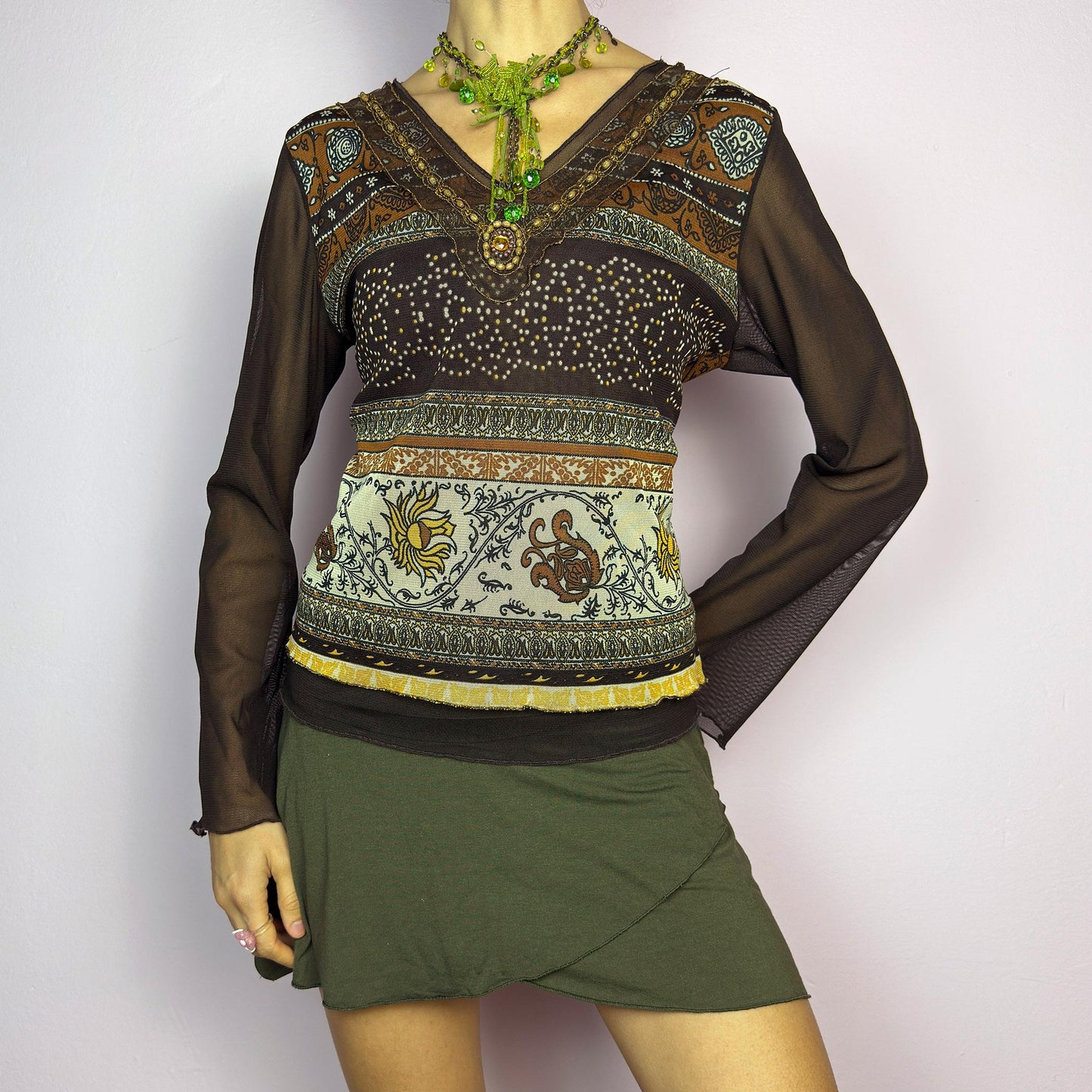 The Y2K Brown Bell Sleeve Mesh Top is a vintage 2000s piece featuring a semi-sheer mesh fabric with baroque and floral-inspired prints. Designed with flared bell sleeves, a fitted silhouette, and a layered hem, this top embodies a dreamy bohemian aesthetic. The lightweight and stretchy fabric make it perfect for ethereal, fairy-grunge looks. adult world shop
