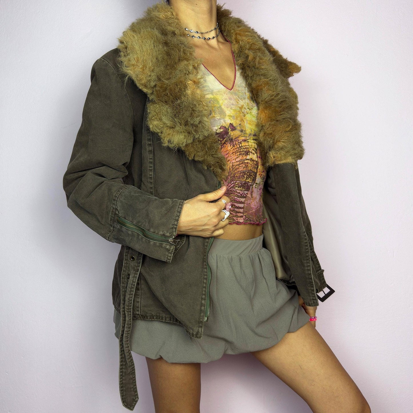 The Y2K Khaki Belted Jacket is a vintage 2000s piece featuring a structured fit with rugged utility-inspired details. Designed with padded shoulders for a strong silhouette, an oversized plush faux-shearling collar, asymmetric zip closure, and an adjustable waist belt for a cinched look. The washed khaki tone and distressed finish add to its edgy, worn-in appeal, making it perfect for grunge or military-inspired winter outfits. A outerwear piece for layering in colder seasons. adult world shop