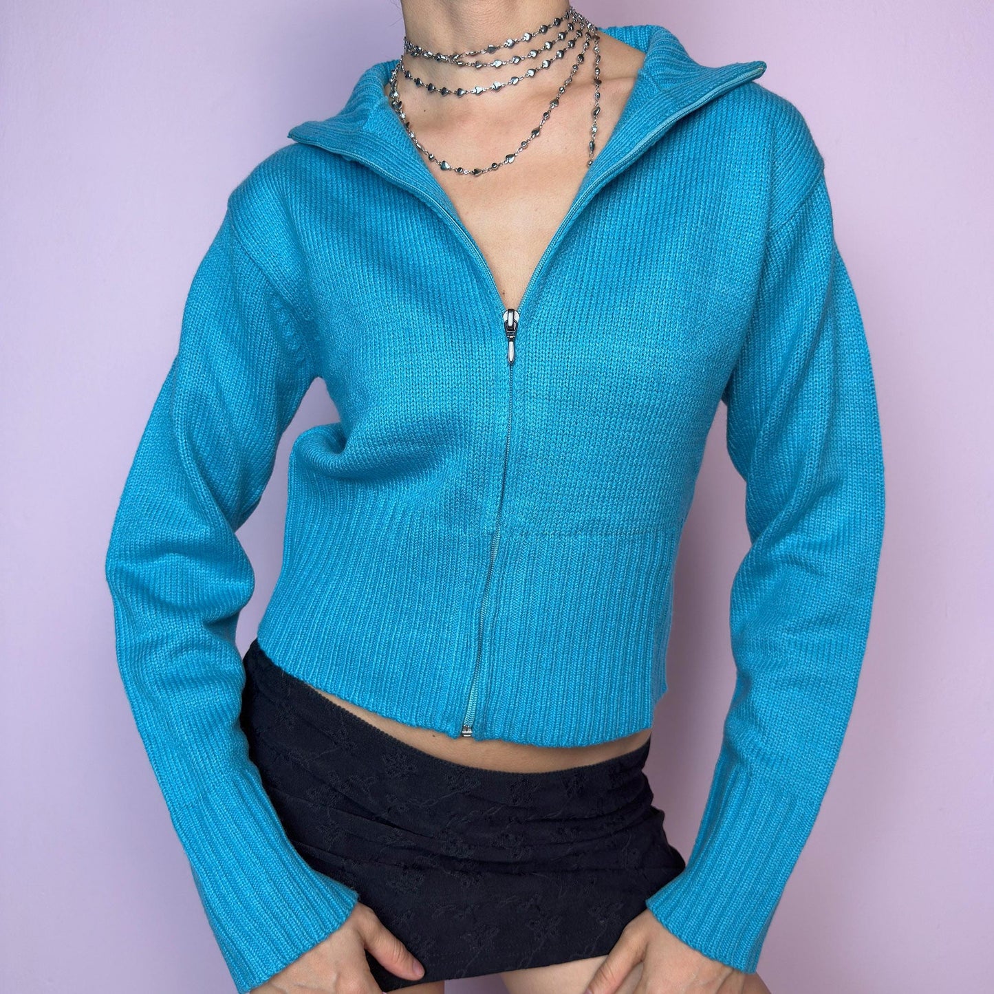 The Y2K Blue Zip Cardigan is a vintage 2000s cropped zip-up knit featuring a vibrant aqua blue tone, a flattering fitted silhouette, a wide collar, and ribbed hem and cuffs. Ideal for layering or adding a pop of color to your casual autumn outfits. Excellent vintage condition. adult world shop