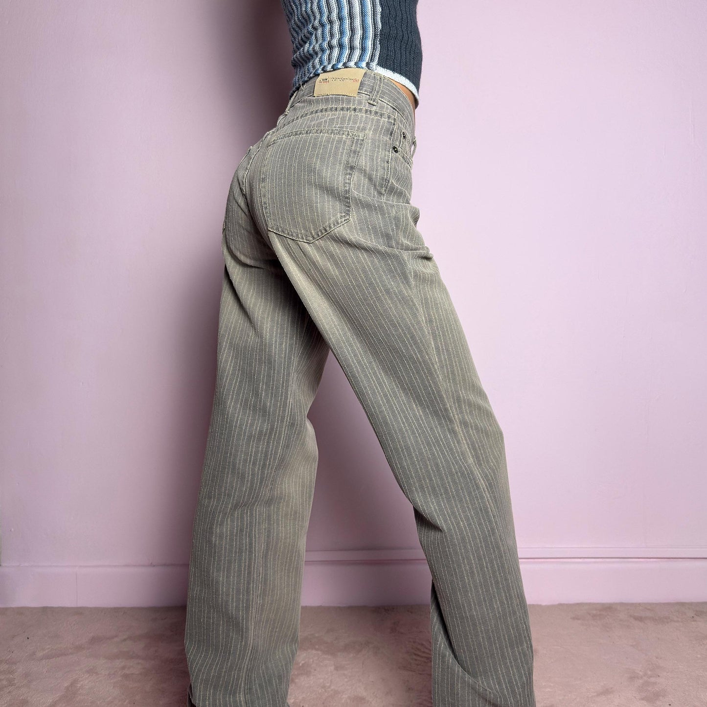The Y2K Gray Straight Jeans are a vintage 2000s essential featuring a structured fabric with subtle pinstripes. Designed with a relaxed straight-leg fit, a flattering high waist, button and zipper closure, and pockets, these jeans offer a sleek yet effortless silhouette. Perfect for casual outfits. adult world shop