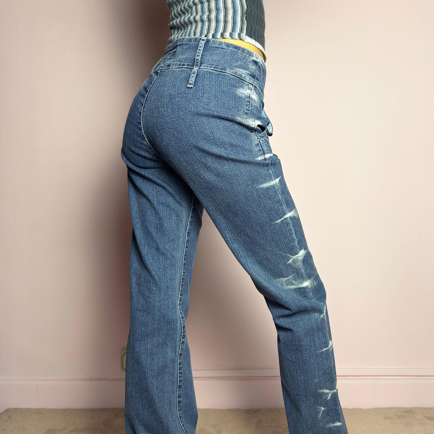 The Y2K Straight-Flare Jeans are a vintage 2000s piece featuring a stretchy denim fabric with a unique painted or bleached streak effect. Designed with a flattering low-rise fit, a slightly flared straight leg, button and zipper closure, and pockets, these jeans offer a sleek silhouette perfect for casual outfits. adult world shop
