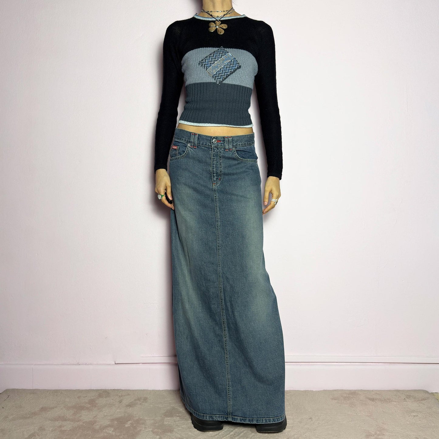 The Y2K Denim Maxi Skirt is a vintage 2000s essential featuring a structured denim fabric in a classic blue wash with subtle fading details. Designed with a mid-rise fit, button and zipper closure, and functional pockets, this skirt offers a sleek yet relaxed silhouette. The back slit adds ease of movement, making it perfect for casual everyday wear. adult world shop