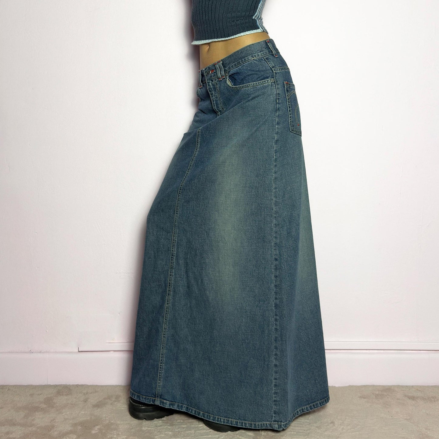 The Y2K Denim Maxi Skirt is a vintage 2000s essential featuring a structured denim fabric in a classic blue wash with subtle fading details. Designed with a mid-rise fit, button and zipper closure, and functional pockets, this skirt offers a sleek yet relaxed silhouette. The back slit adds ease of movement, making it perfect for casual everyday wear. adult world shop