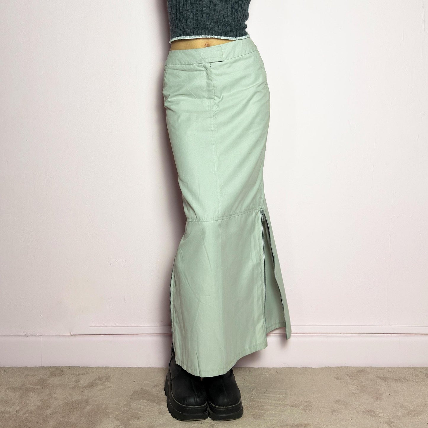 The Y2K Light Gray Maxi Skirt is a vintage 2000s piece with a sleek, futuristic aesthetic. Featuring a structured fit, and a high-rise waist, this skirt is designed for a modern, minimal look. Made from lightweight fabric, it offers a flattering silhouette with dual side zipper slits for adjustable styling. Perfect for casual, streetwear, or cyber-inspired avant-garde outfits. adult world shop