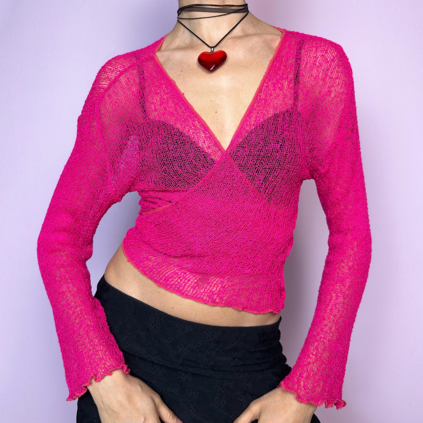 The Y2K Pink Sheer Knit Tie Cardigan is a feminine vintage 2000s bolero-style piece featuring a sheer open-knit texture, ruffled lettuce hems, a vibrant hot pink hue and three quarter sleeves. Stretchy and versatile, it can be tied at the front for a more fitted silhouette. Perfect for clubwear, festival styling, or layering for casual summer outfits. adult world shop