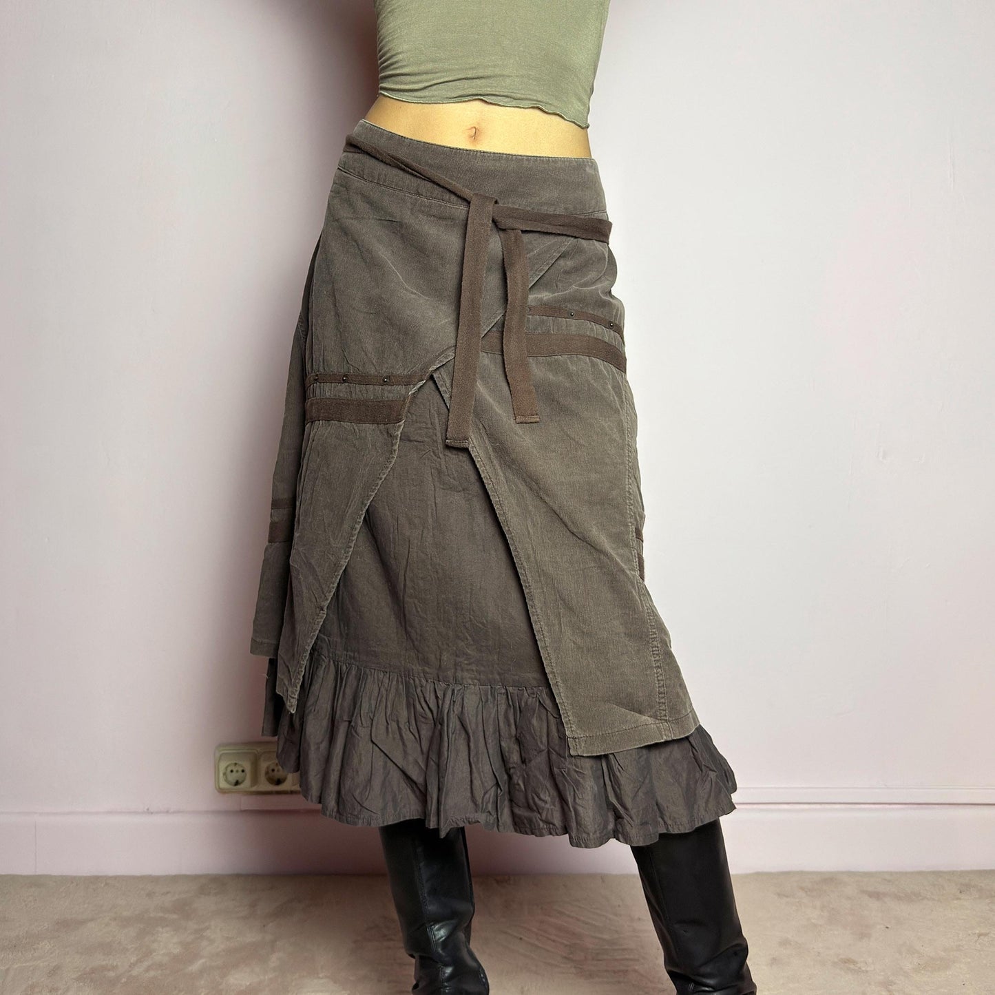 The Y2K Layered Brown Midi Skirt is a unique vintage 2000s piece featuring an asymmetric wrap design with a layered ruffle hem. Made from corduroy-cotton fabric, it includes tie closures for an adjustable fit, a back zipper closure, and subtle stitched detailing that adds a deconstructed touch. Perfect for earthy, bohemian, or avant-garde styling. adult world shop
