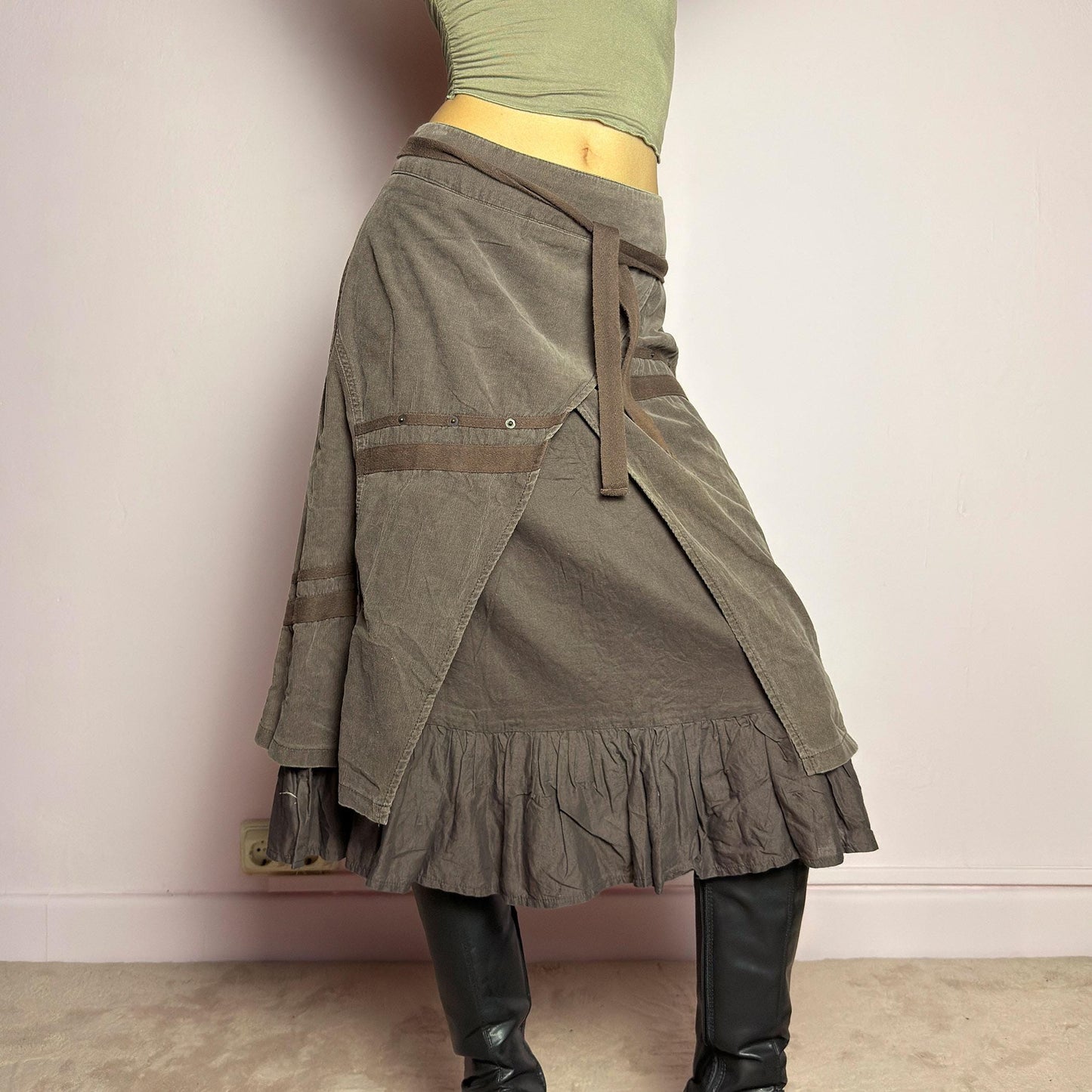 The Y2K Layered Brown Midi Skirt is a unique vintage 2000s piece featuring an asymmetric wrap design with a layered ruffle hem. Made from corduroy-cotton fabric, it includes tie closures for an adjustable fit, a back zipper closure, and subtle stitched detailing that adds a deconstructed touch. Perfect for earthy, bohemian, or avant-garde styling. adult world shop
