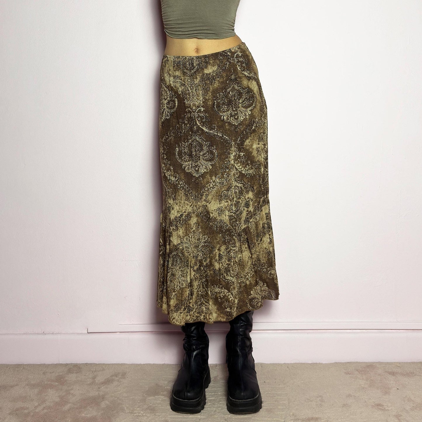 The Y2K Brown Paisley Midi Skirt is a vintage 2000s piece featuring a baroque-inspired paisley print. Designed with an earthy, whimsical aesthetic, this skirt has a flowy silhouette with subtle ruffle tiered details at the hem. It features a side zipper closure with an elastic waist. Perfect for grunge and bohemian-inspired outfits. adult world shop