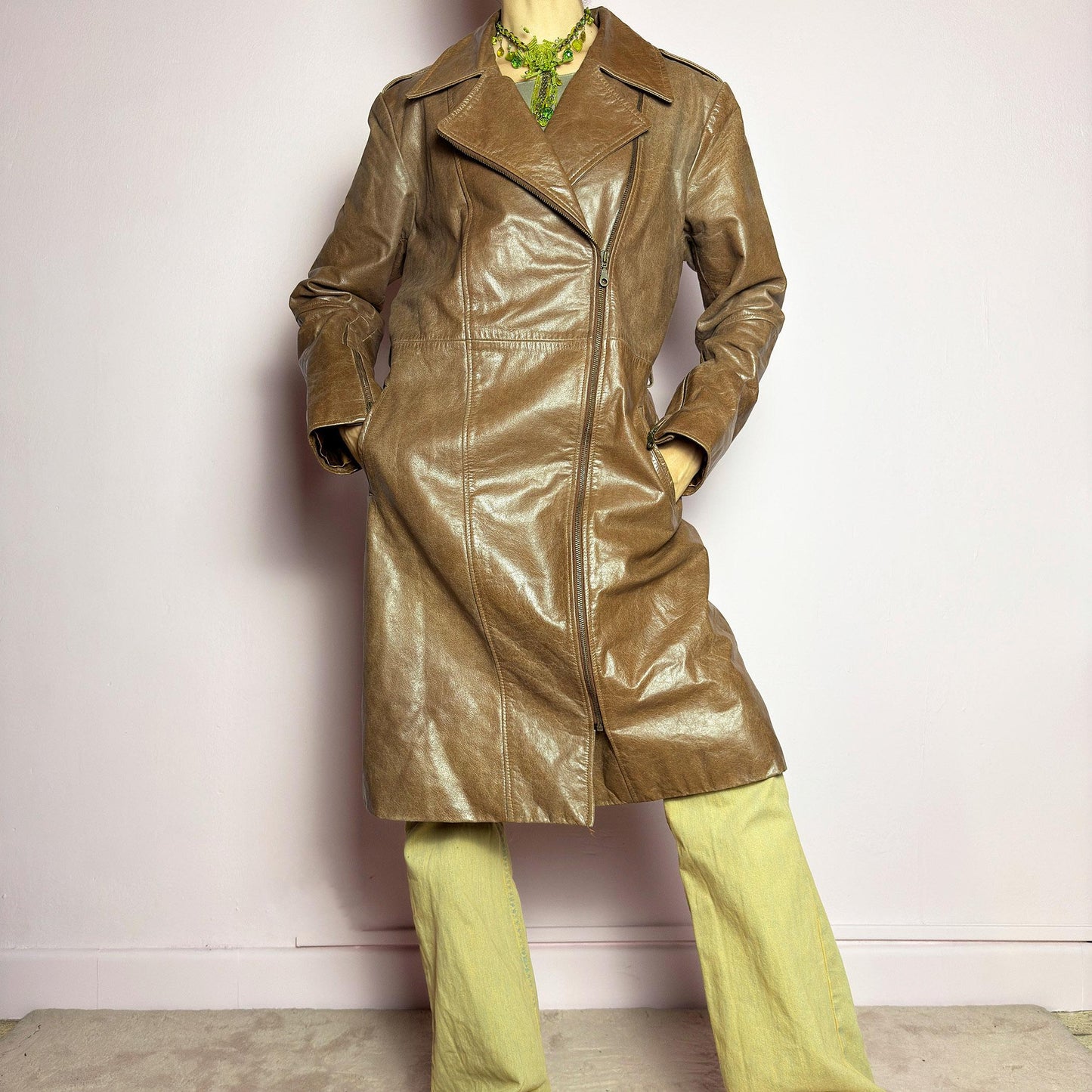 The Y2K Long Brown Leather Coat is a heavy, structured vintage 2000s piece crafted from genuine leather. It features an asymmetrical zip closure, a wide lapel collar, and a belted waist for a cinched silhouette. The coat includes pockets and a smooth lining for comfort. With its durable construction and timeless design, this vintage long leather coat is perfect for edgy streetwear or sophisticated layering. adult world shop