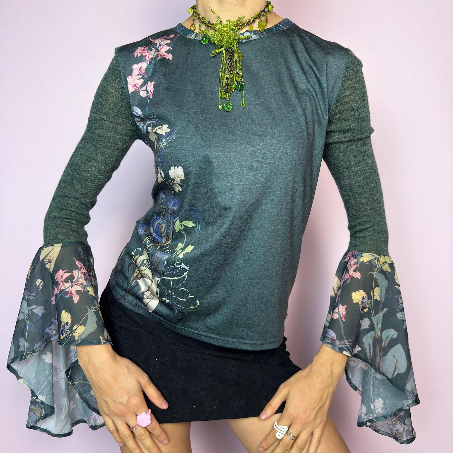 The Y2K Green Bell Sleeve Top is a rare vintage 2000s piece with ethereal vibes. Features stretchy semi-sheer forest green fabric with a romantic floral print on one side and dramatic bell sleeves adorned with matching botanical motifs. Soft and lightweight. Perfect for fairycore and festival looks. Great vintage condition.