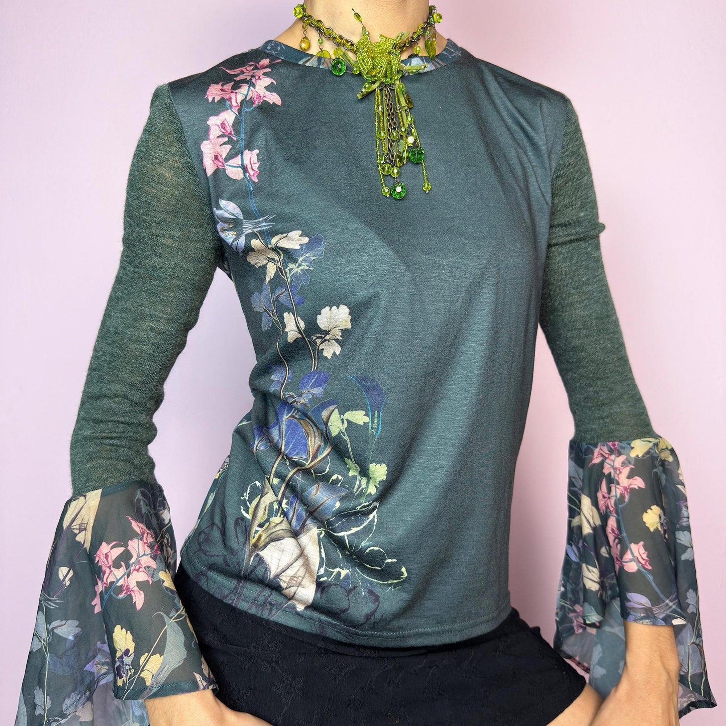 The Y2K Green Bell Sleeve Top is a rare vintage 2000s piece with ethereal vibes. Features stretchy semi-sheer forest green fabric with a romantic floral print on one side and dramatic bell sleeves adorned with matching botanical motifs. Soft and lightweight. Perfect for fairycore and festival looks. Great vintage condition.