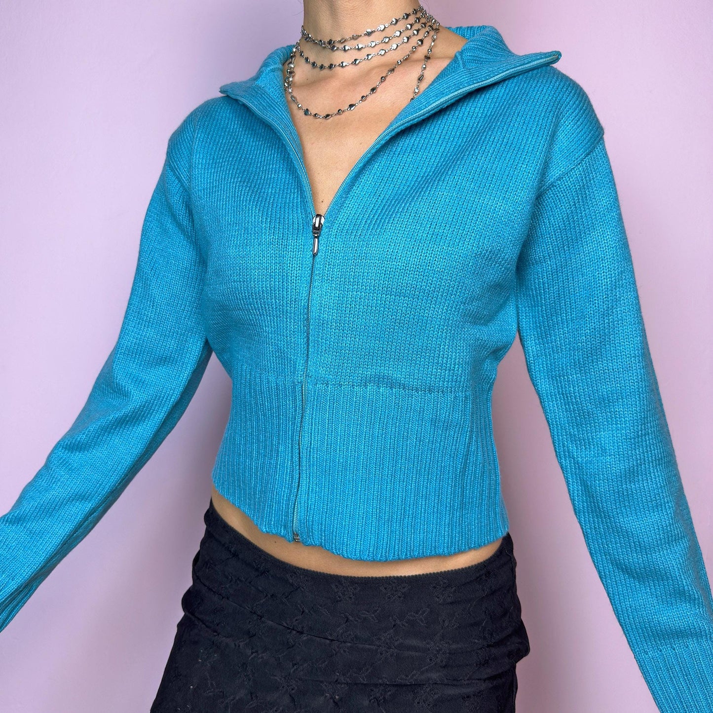The Y2K Blue Zip Cardigan is a vintage 2000s cropped zip-up knit featuring a vibrant aqua blue tone, a flattering fitted silhouette, a wide collar, and ribbed hem and cuffs. Ideal for layering or adding a pop of color to your casual autumn outfits. Excellent vintage condition. adult world shop