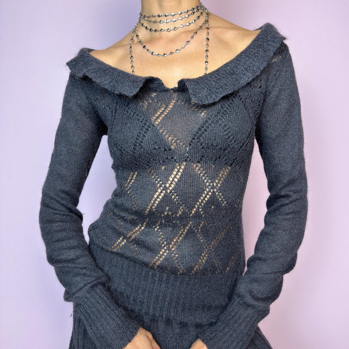 The Y2K Gray Mini Knit Dress is a vintage 2000s piece featuring a ruffled off-shoulder neckline and sheer diamond-knit pattern through the bodice. The fitted waist flows into a pleated mini skirt. Made from a soft, stretchy knit that hugs the body while remaining comfortable. Perfect for casual autumn look. adult world shop