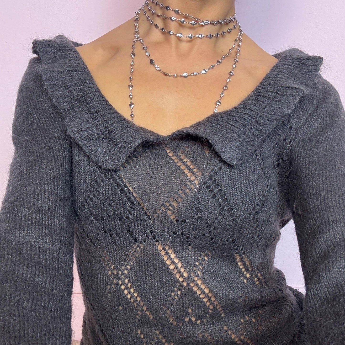 The Y2K Gray Mini Knit Dress is a vintage 2000s piece featuring a ruffled off-shoulder neckline and sheer diamond-knit pattern through the bodice. The fitted waist flows into a pleated mini skirt. Made from a soft, stretchy knit that hugs the body while remaining comfortable. Perfect for casual autumn look. adult world shop