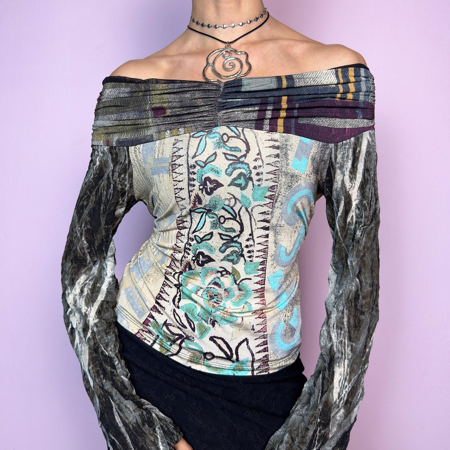 The Y2K Art Print Top is a vintage 2000s off-the-shoulder long sleeve designed by Legatte Jeans. This artsy piece features a unique patchwork-style mixed print with floral, stripe, and abstract motifs in a moody palette of cream, sage, burgundy, and metallic gray. The body is made from soft, stretchy fabric, while the semi-sheer mesh sleeves add a delicate contrast. Pleated details along the neckline elevate its sculptural silhouette. adult world shop