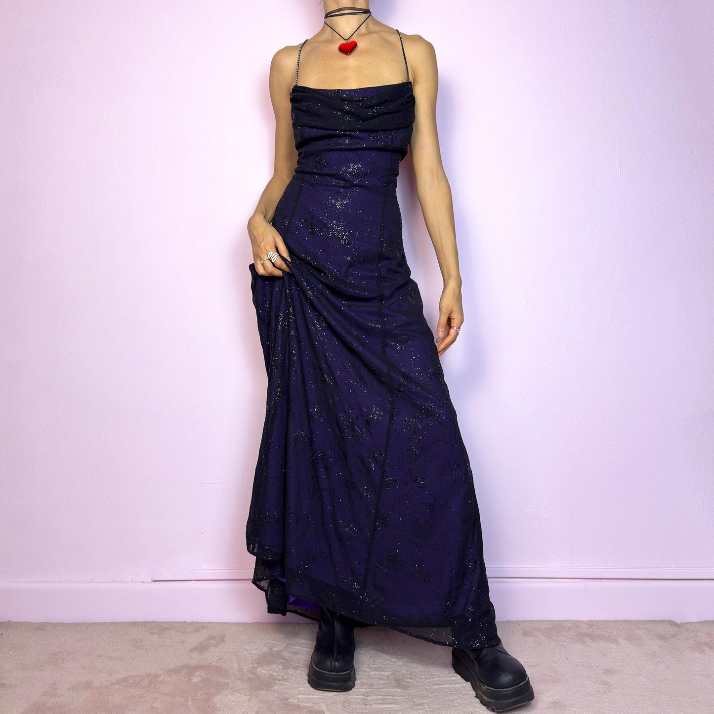 Step into the night in this breathtaking vintage 90s formal black glitter maxi dress. Crafted from a deep purple base with a sheer black overlay, it features all-over subtle glitter details that catch the light with every move. The draped cowl neckline adds soft elegance, while the delicate spaghetti straps are adorned with shimmering rhinestones for that extra sparkle. Designed with a flattering fit and a back zipper closure for ease and shape. A rare celestial piece – ideal for prom.