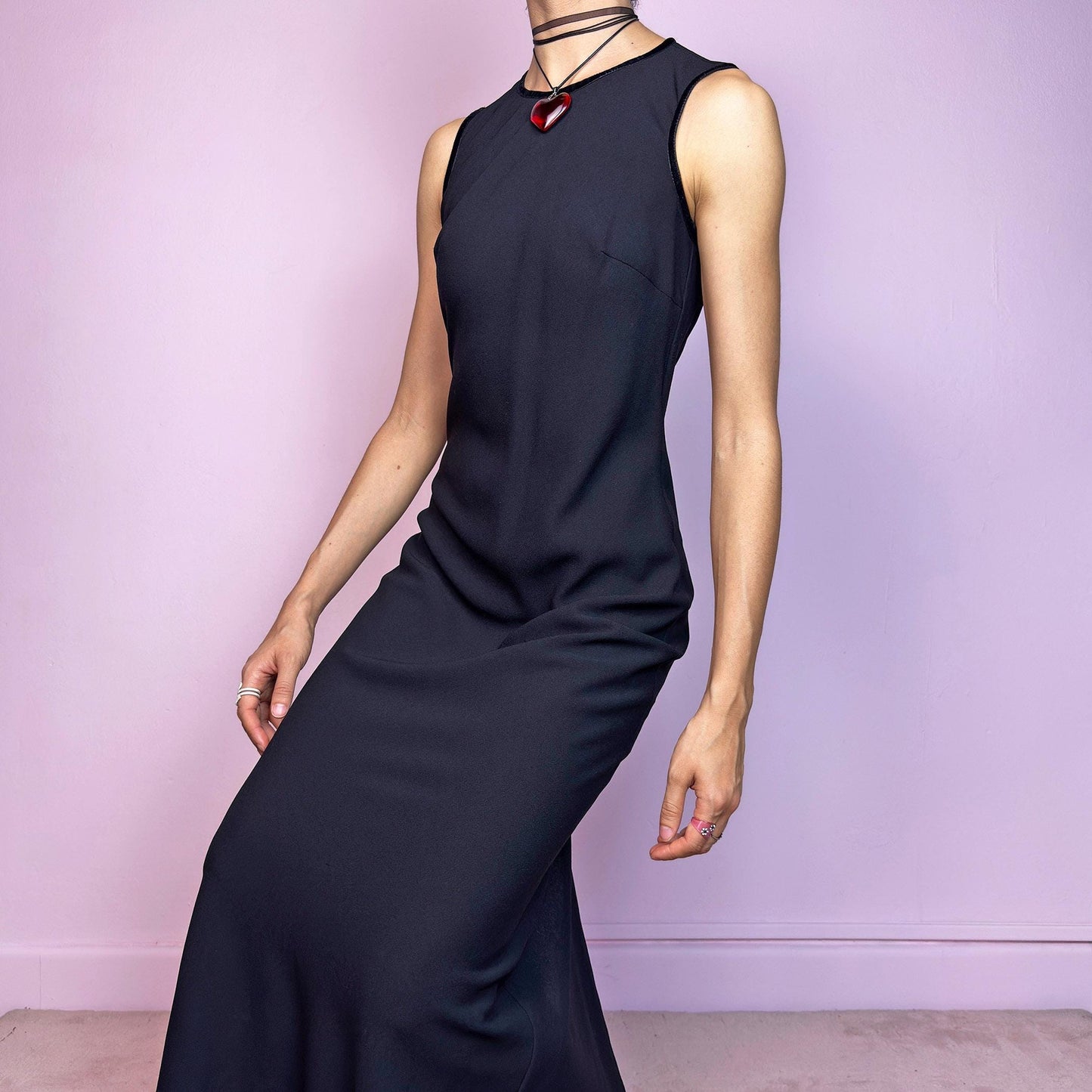 The Y2K Minimalist Black Midi Dress is a vintage 2000s sleek and timeless piece featuring a sleeveless design, and a slim, flattering fit. Crafted with lightweight, slightly sheer fabric, it drapes beautifully along the body and ends in a classic midi length. Features a back zipper closure and a back slit for ease of movement and an elegant touch. Perfect for minimalist, officecore, or elegant 90s-inspired looks. Effortlessly versatile for both casual layering and dressier night-out outfits.
