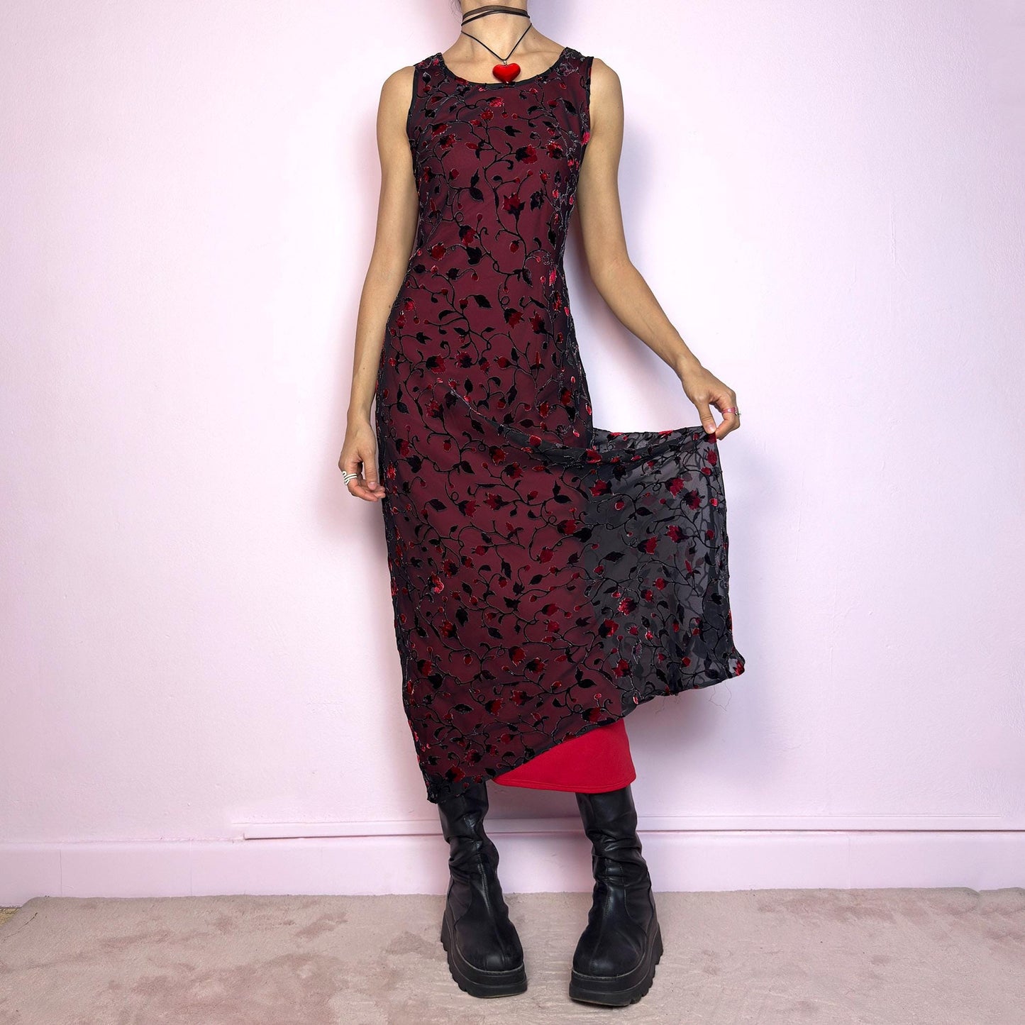 The Vintage 90s Black Sheer Floral Midi Dress is a striking piece featuring a sheer black overlay with textured velvet floral details layered over a vibrant red lining. The sleeveless design and round neckline offer a timeless silhouette, while the fitted shape and midi length create a flattering, romantic look. The fabric is slightly stretchy and flowy, with a gothic romantic vibe perfect for dark fairycore, witchy looks, or 2000s party aesthetics. Excellent vintage condition.
